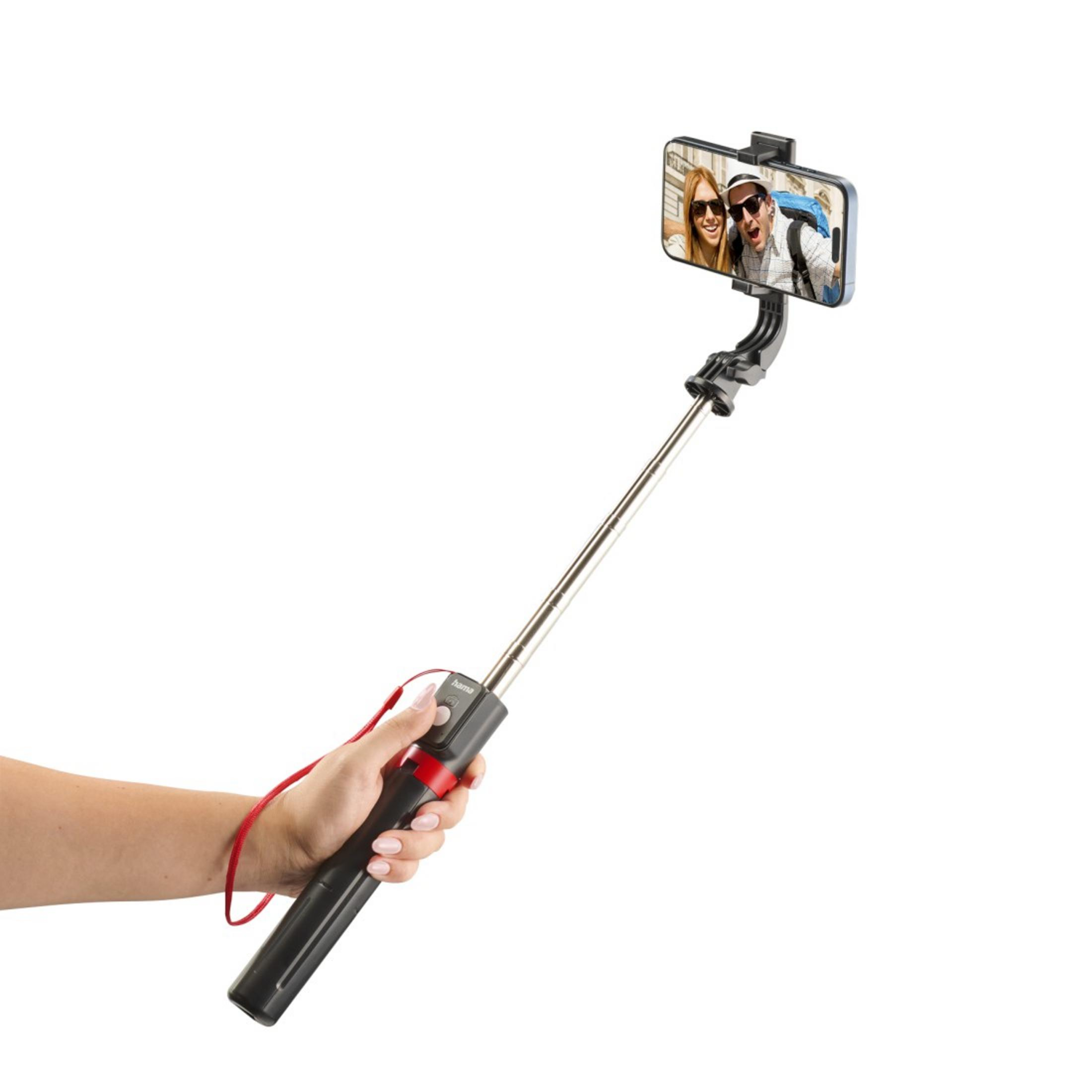 Una mano tiene un selfie stick con uno smartphone che mostra una coppia.