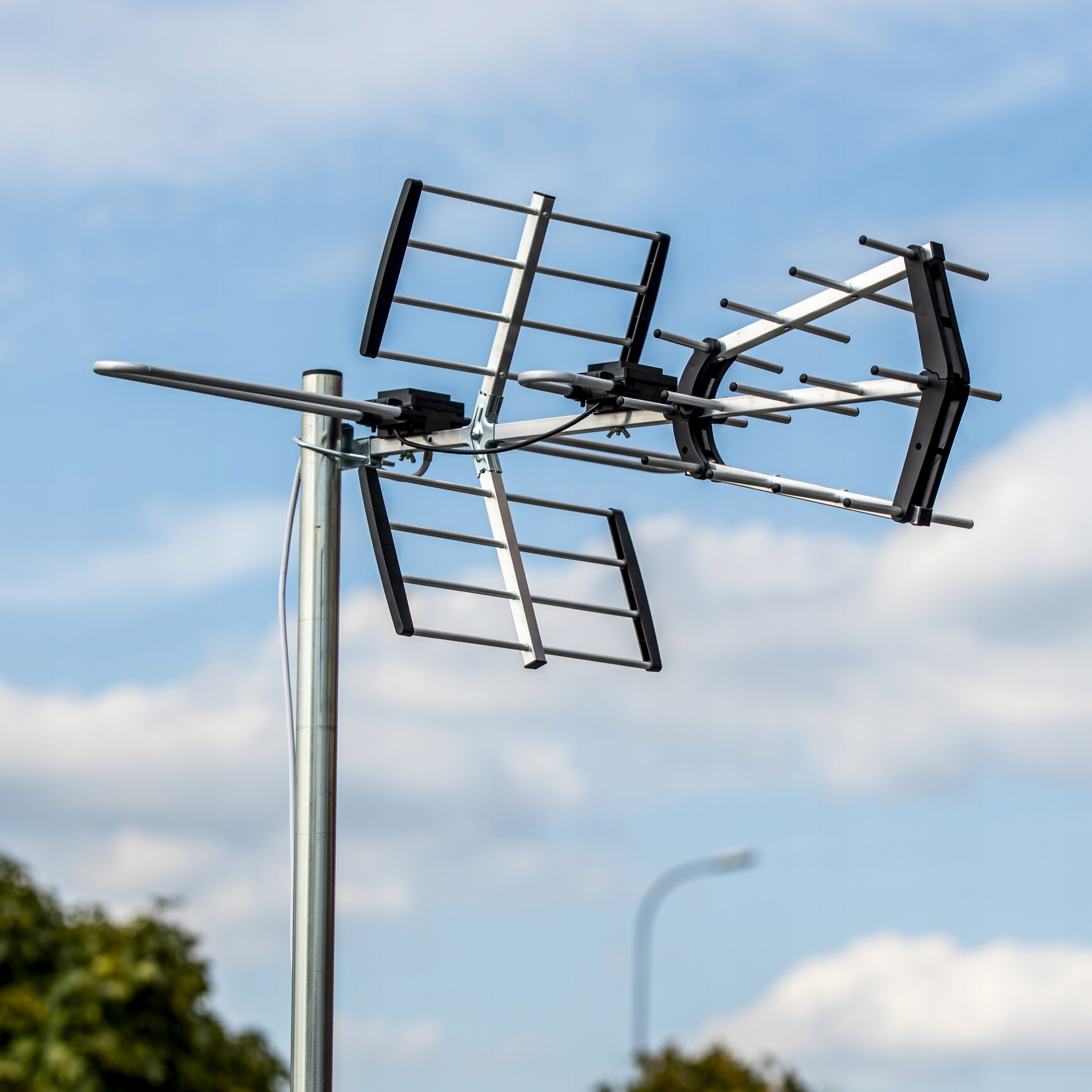 Antena telewizyjna wieloelementowa zamontowana na słupie na tle niebieskiego nieba.