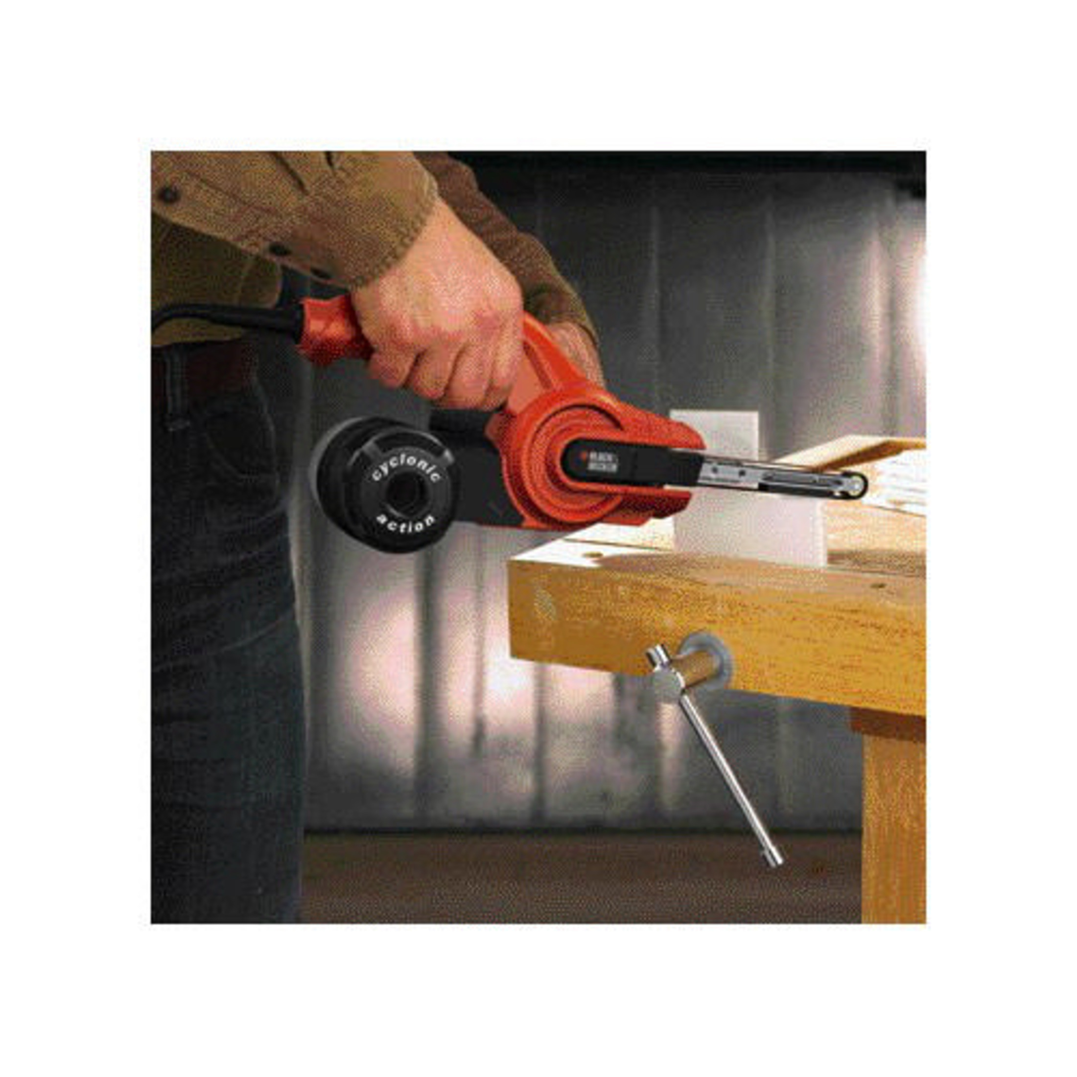 Ein Mann schleift mit einem orangen Black+Decker-Bandschleifer Holz, das in einem Schraubstock eingespannt ist.
