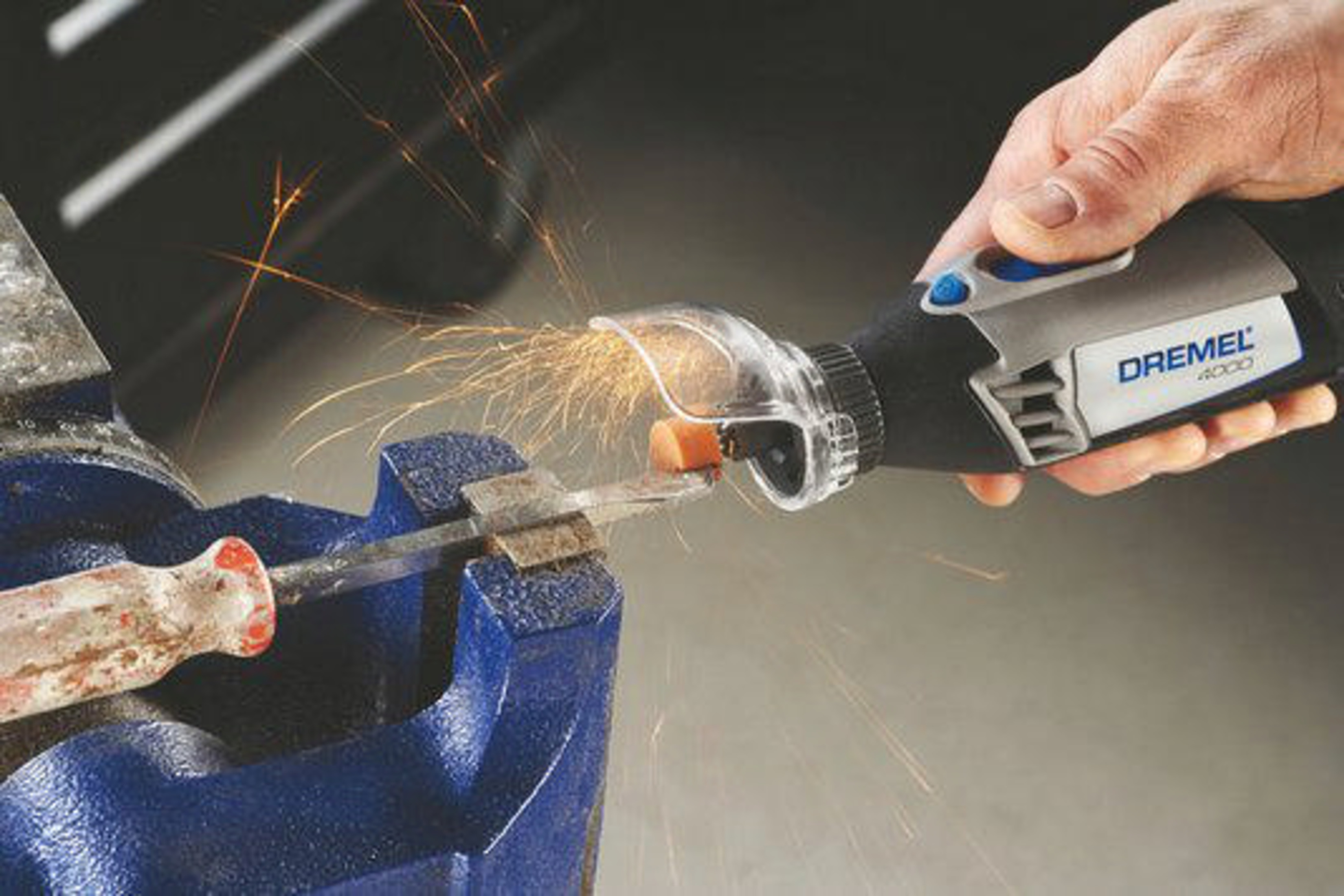Narzędzie Dremel 4000 szlifuje metal w niebieskim imadle, lecą iskry.