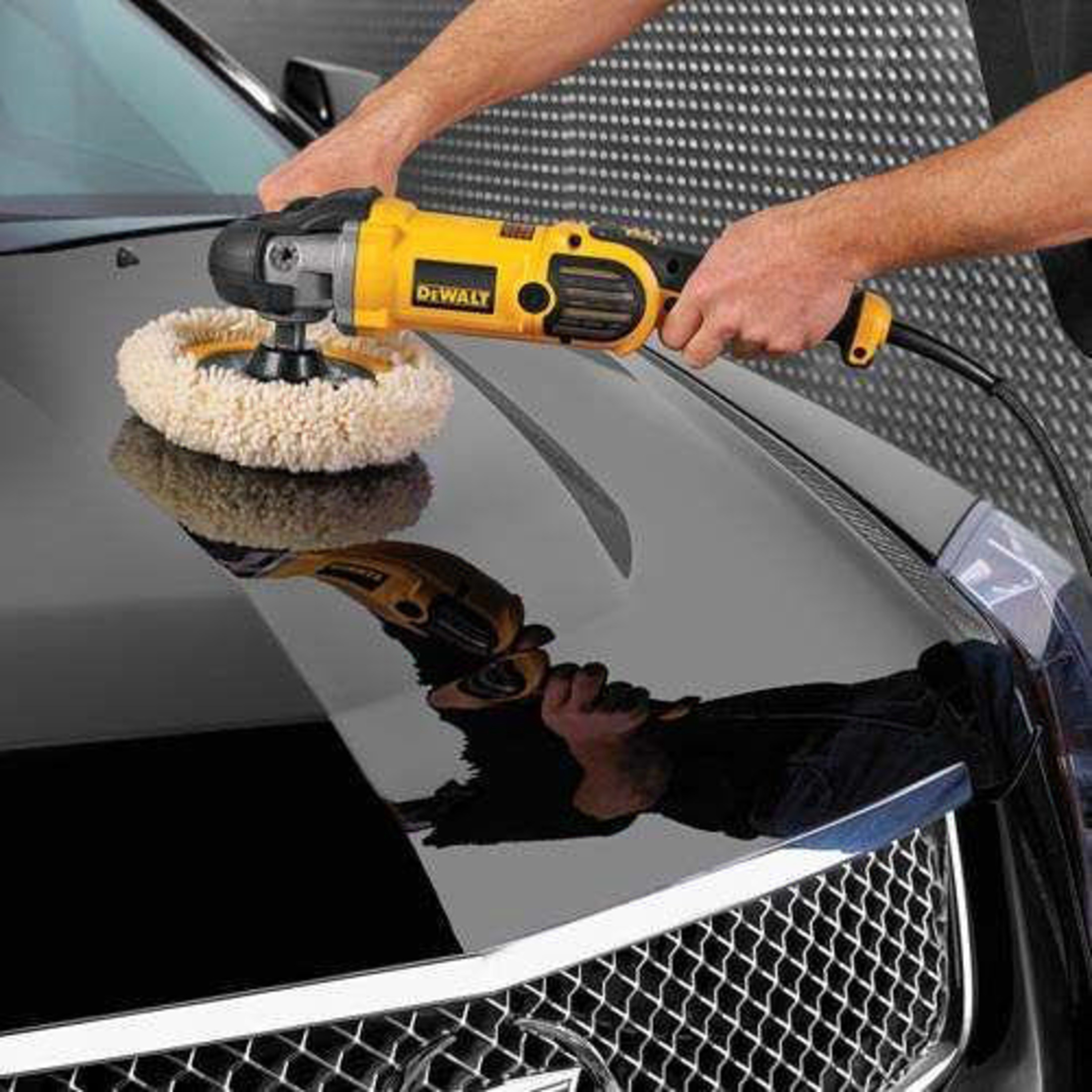 Homme lustrant une voiture noire avec une lustreuse jaune