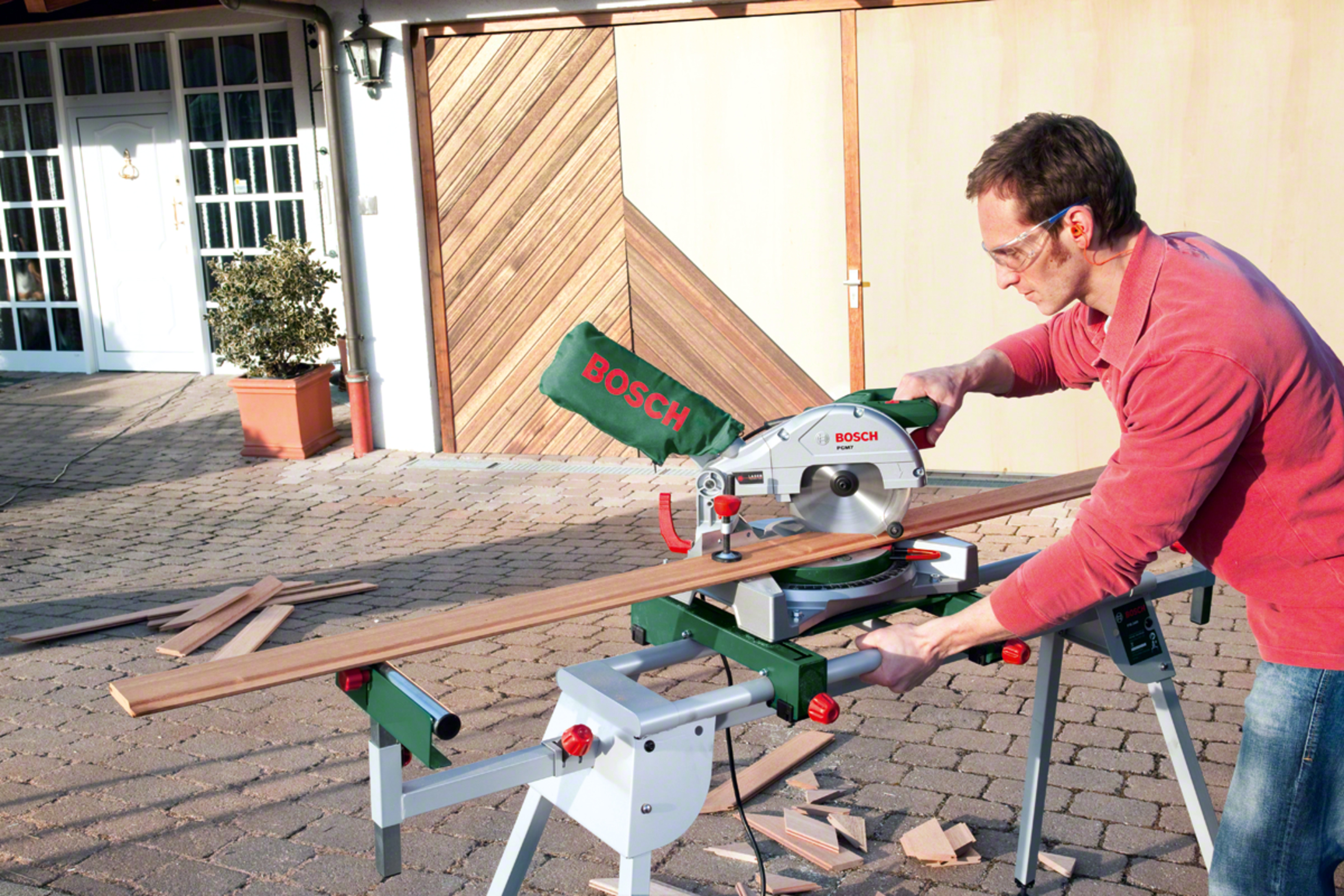 Mann schneidet Holz mit Bosch-Säge im Freien. Nahaufnahme.