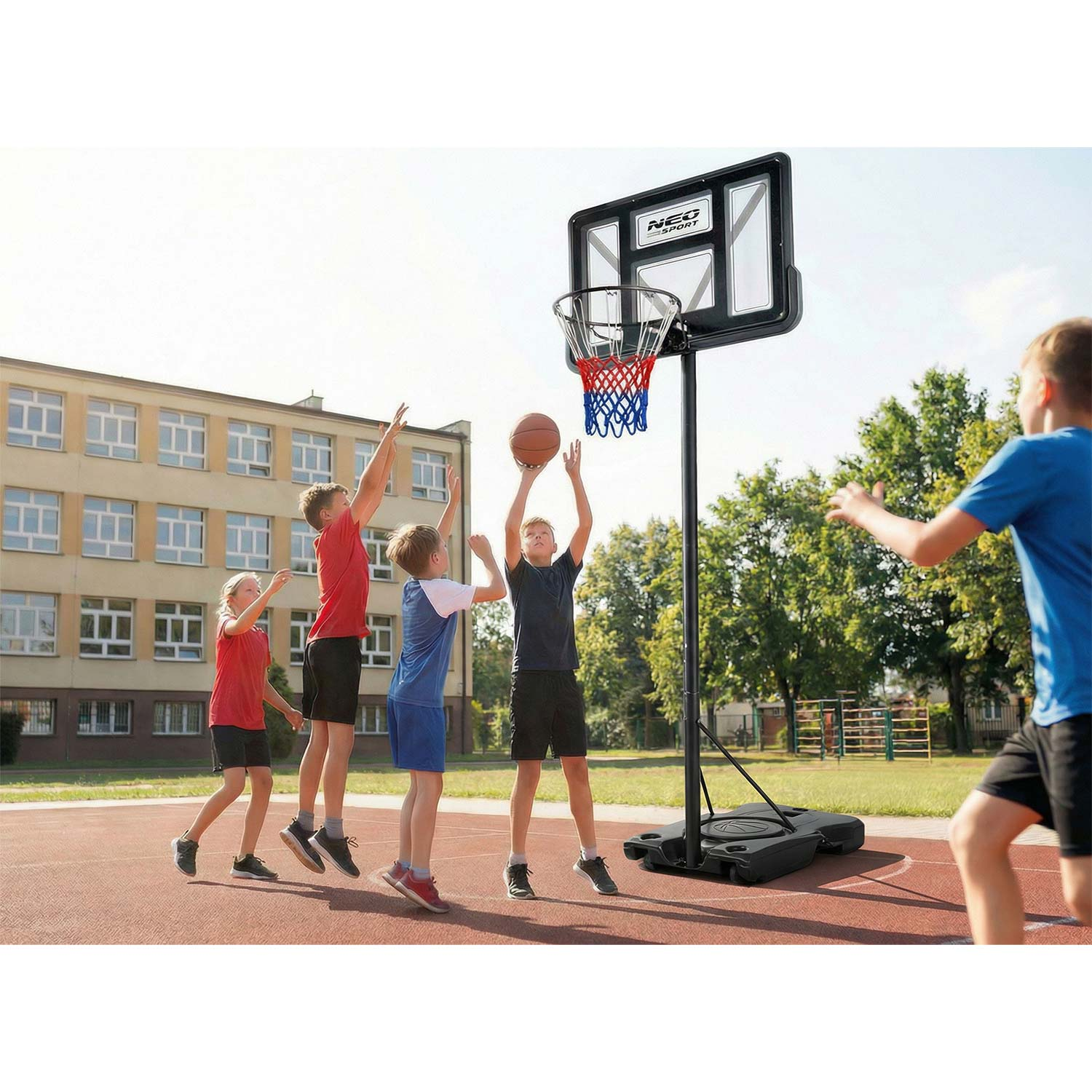 Dzieci grają w koszykówkę na boisku przed szkołą.