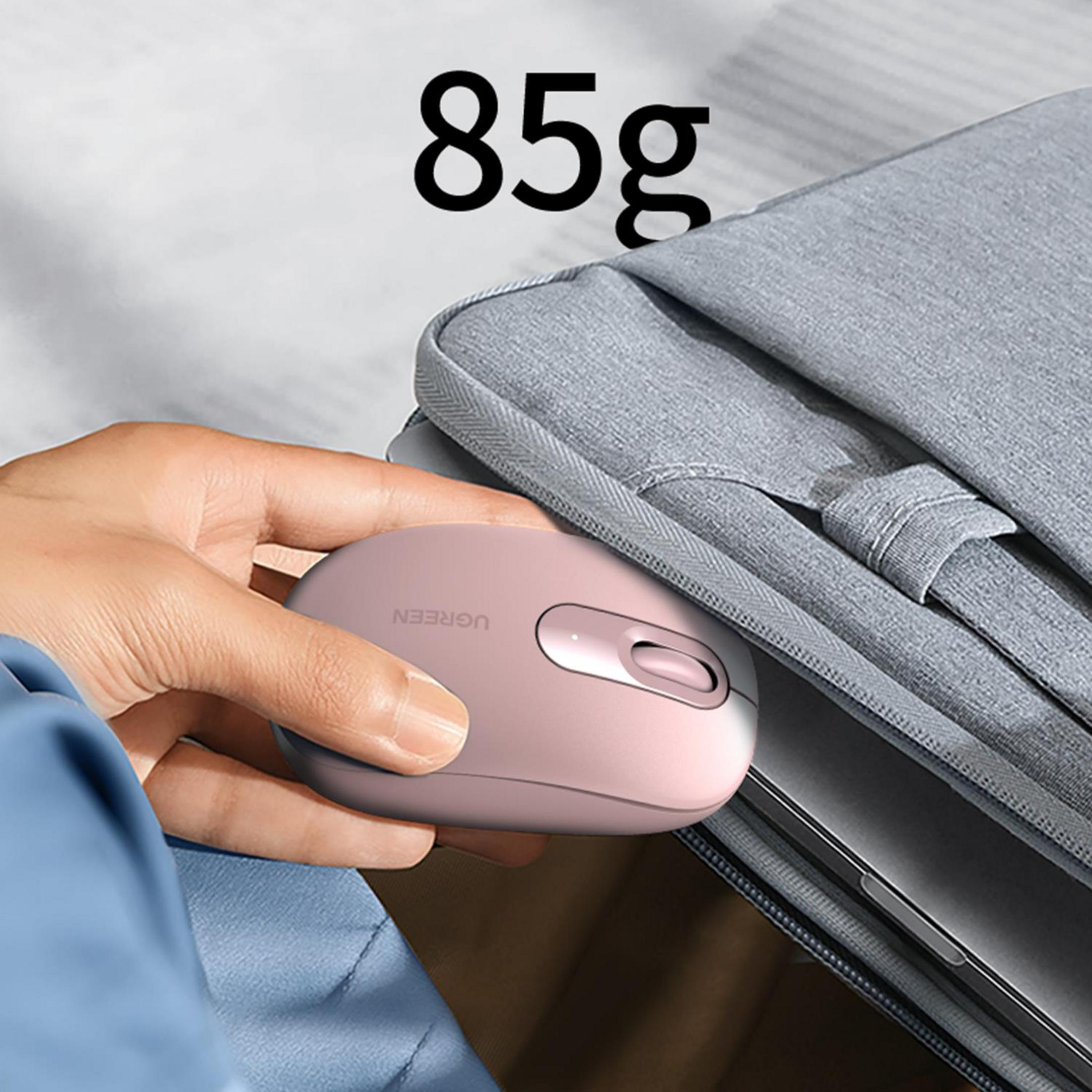 Una mano tiene un mouse rosa accanto a una borsa grigia con un laptop all'interno.