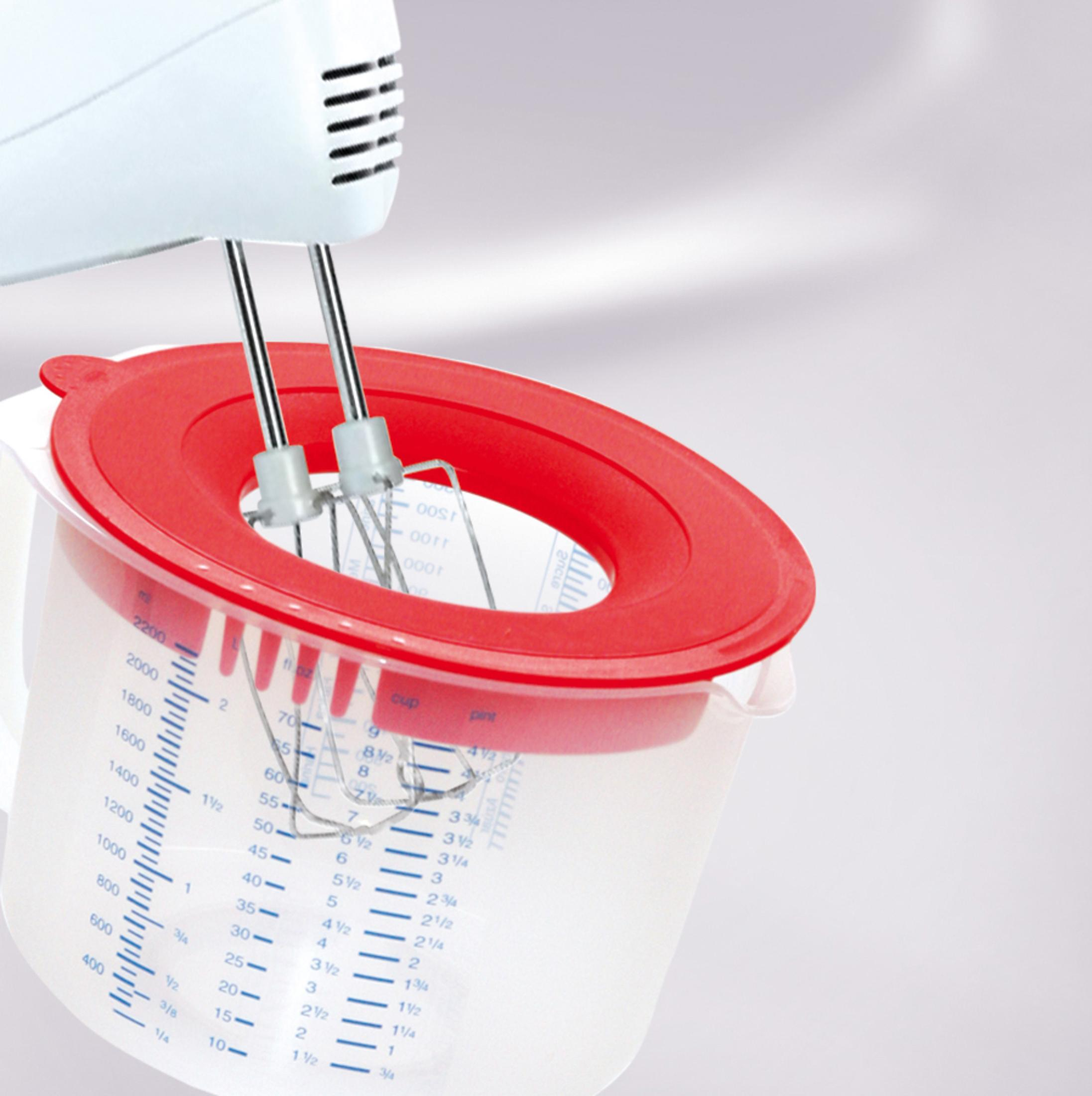 Ein weißer Handmixer mit roten Schlägern über einem Messbecher mit rotem Deckel.