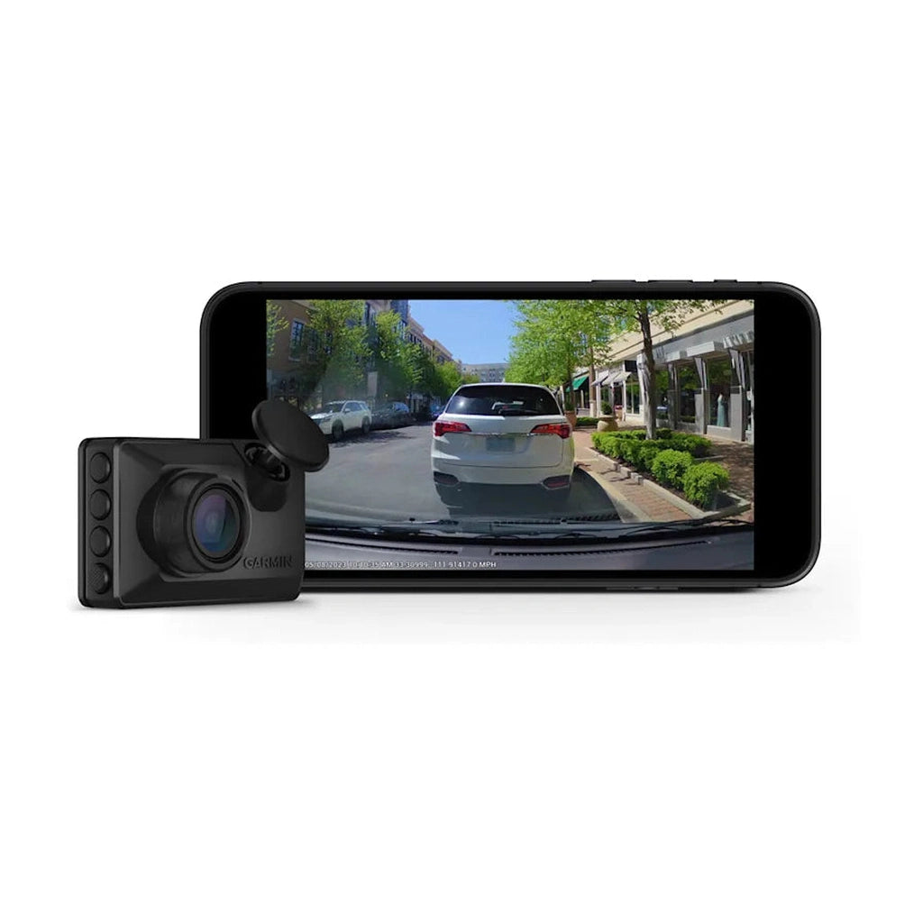 Eine schwarze Garmin-Dashcam neben einem Smartphone, das ein Auto auf einer Straße zeigt.