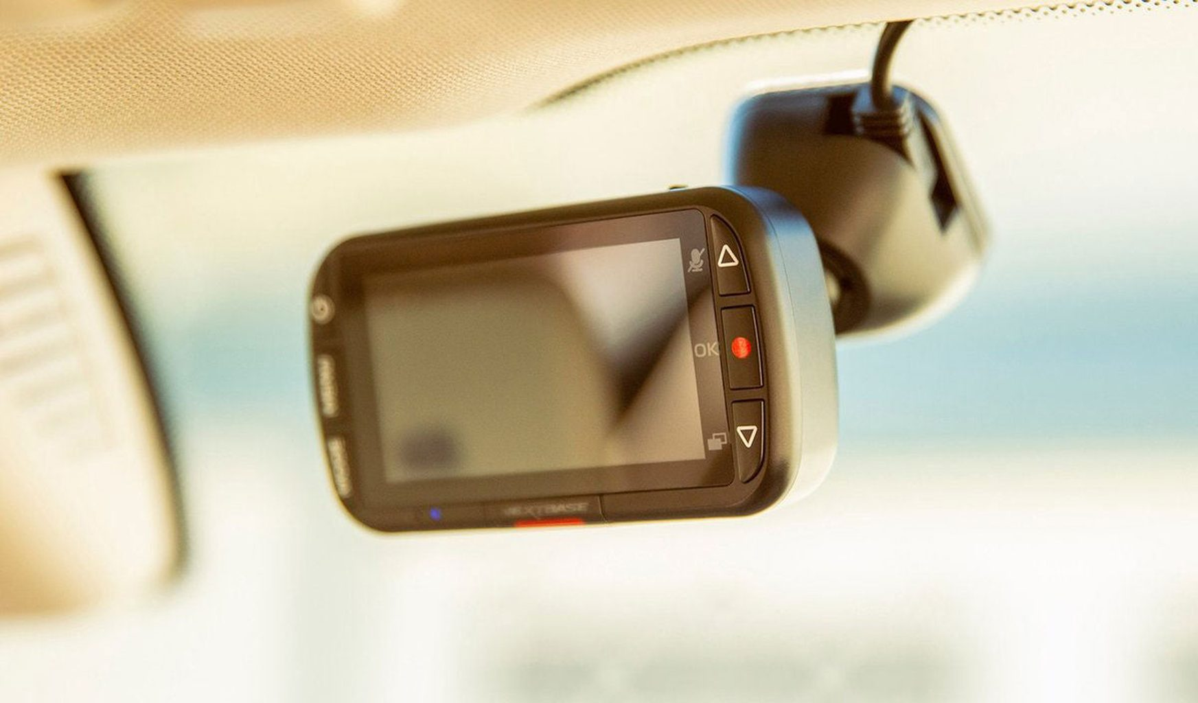 Een zwarte dashcam-recorder is aan de voorruit bevestigd. Hij heeft een display en knoppen.