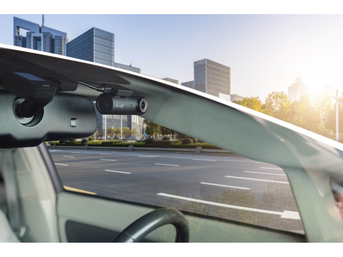Car dashcam mounted on rearview mirror, view of city and road.