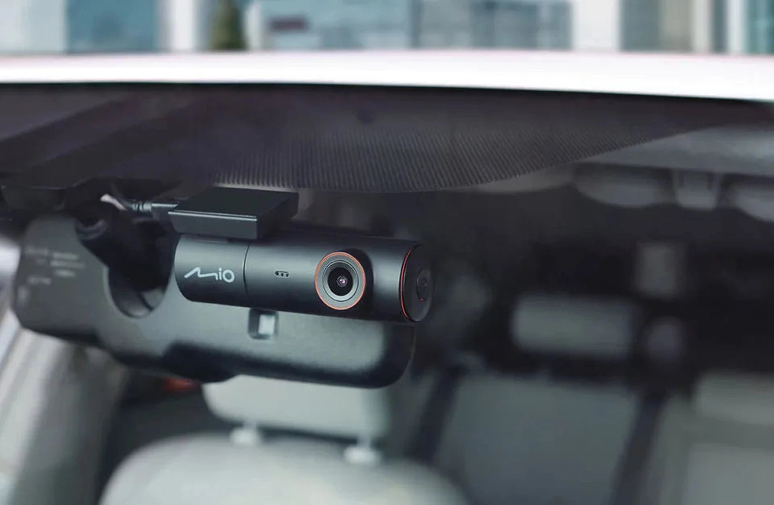 A black Mio dashcam is mounted on the car's windshield.