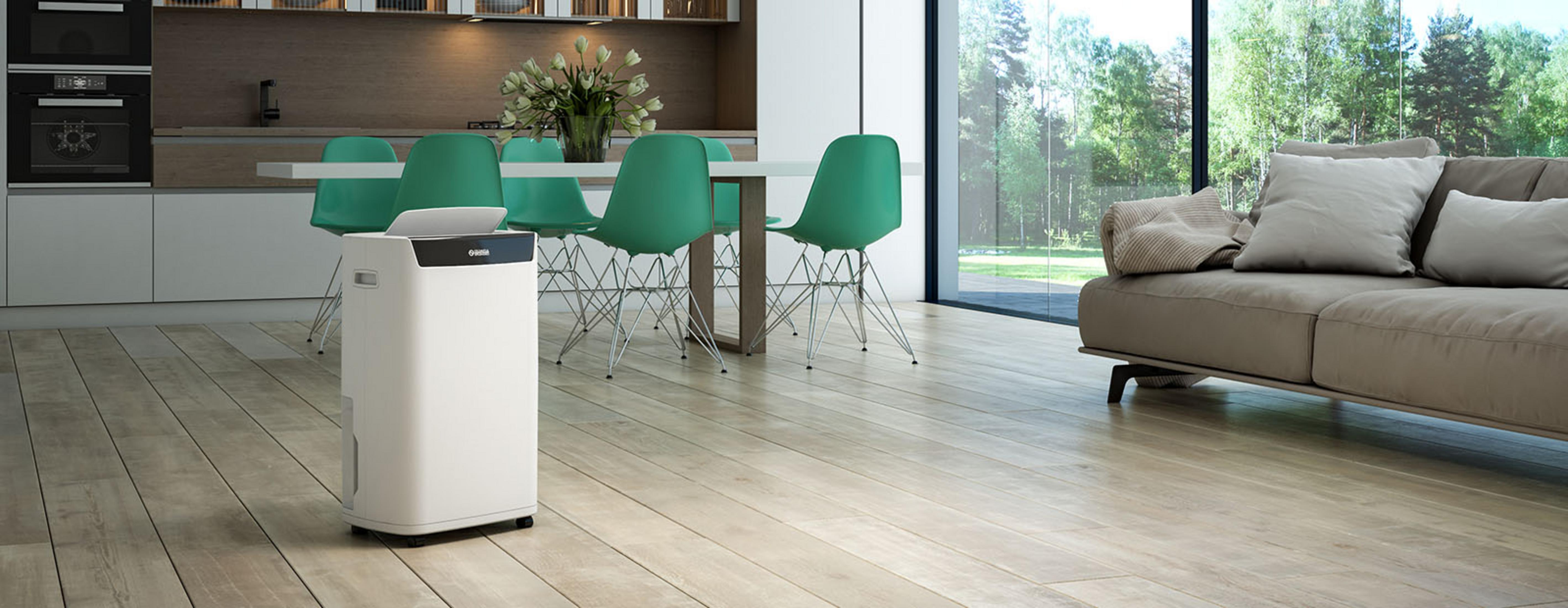 Biały oczyszczacz powietrza na drewnianej podłodze w nowoczesnym salonie z sofą.