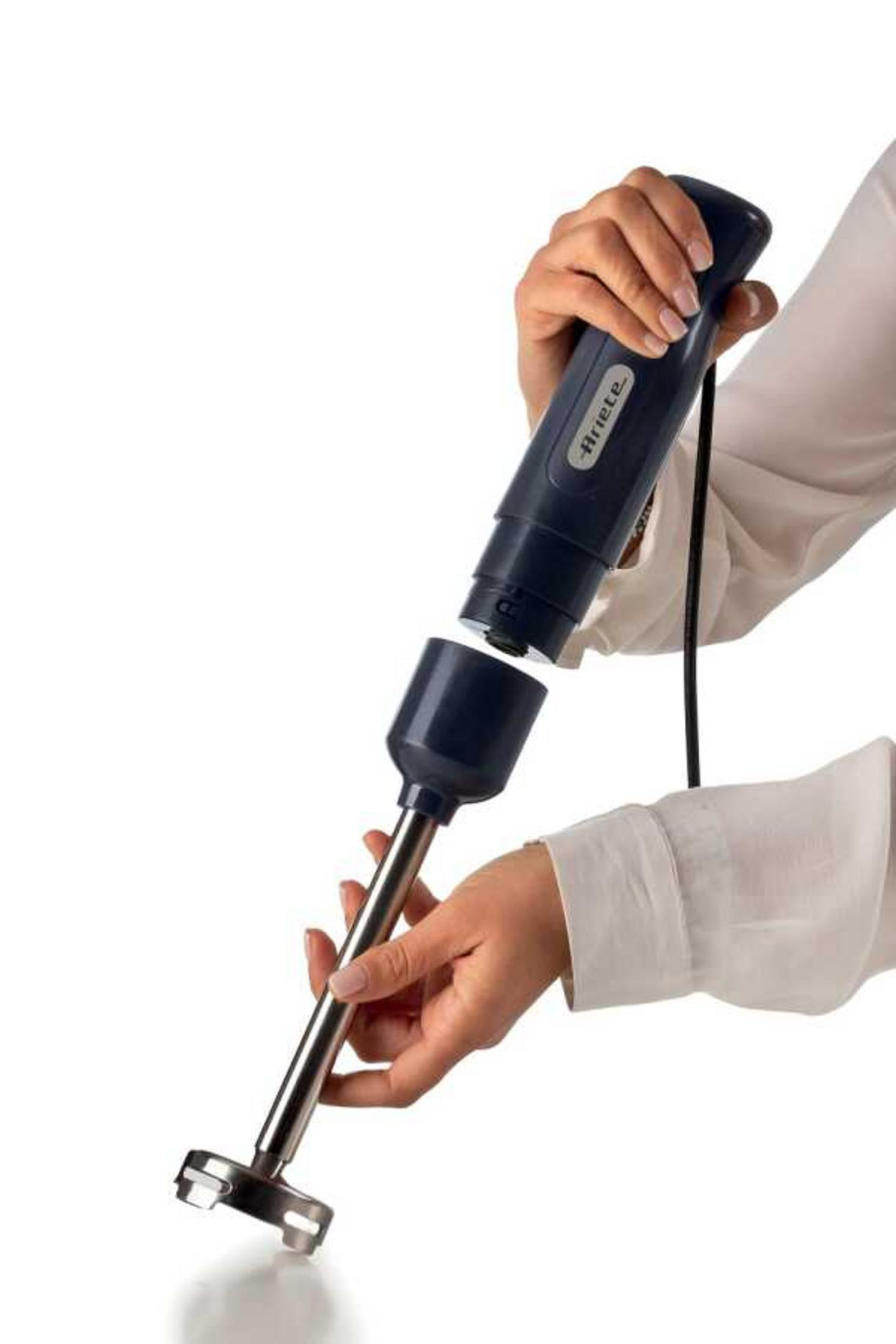 Ręka trzyma ciemny blender ręczny ze srebrną nasadką na białym tle.