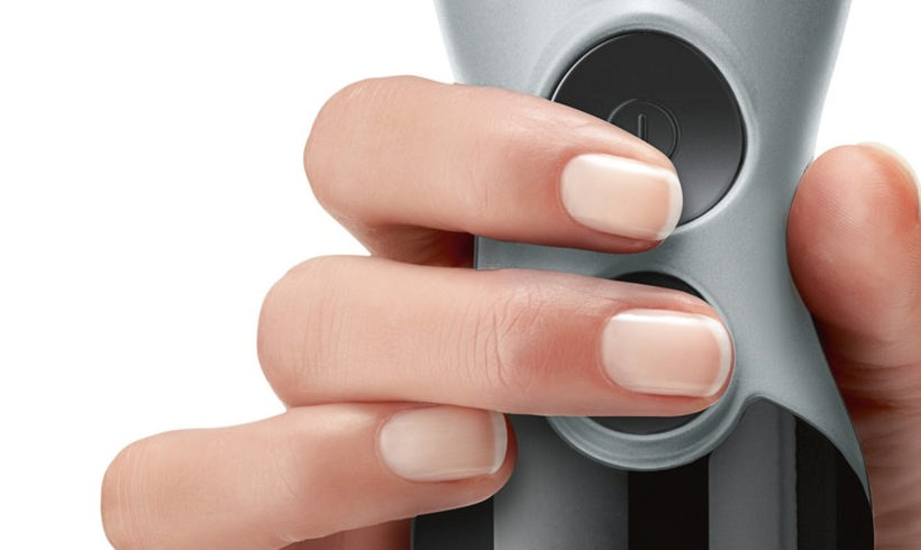 Dłoń naciska czarny przycisk na szarym urządzeniu.