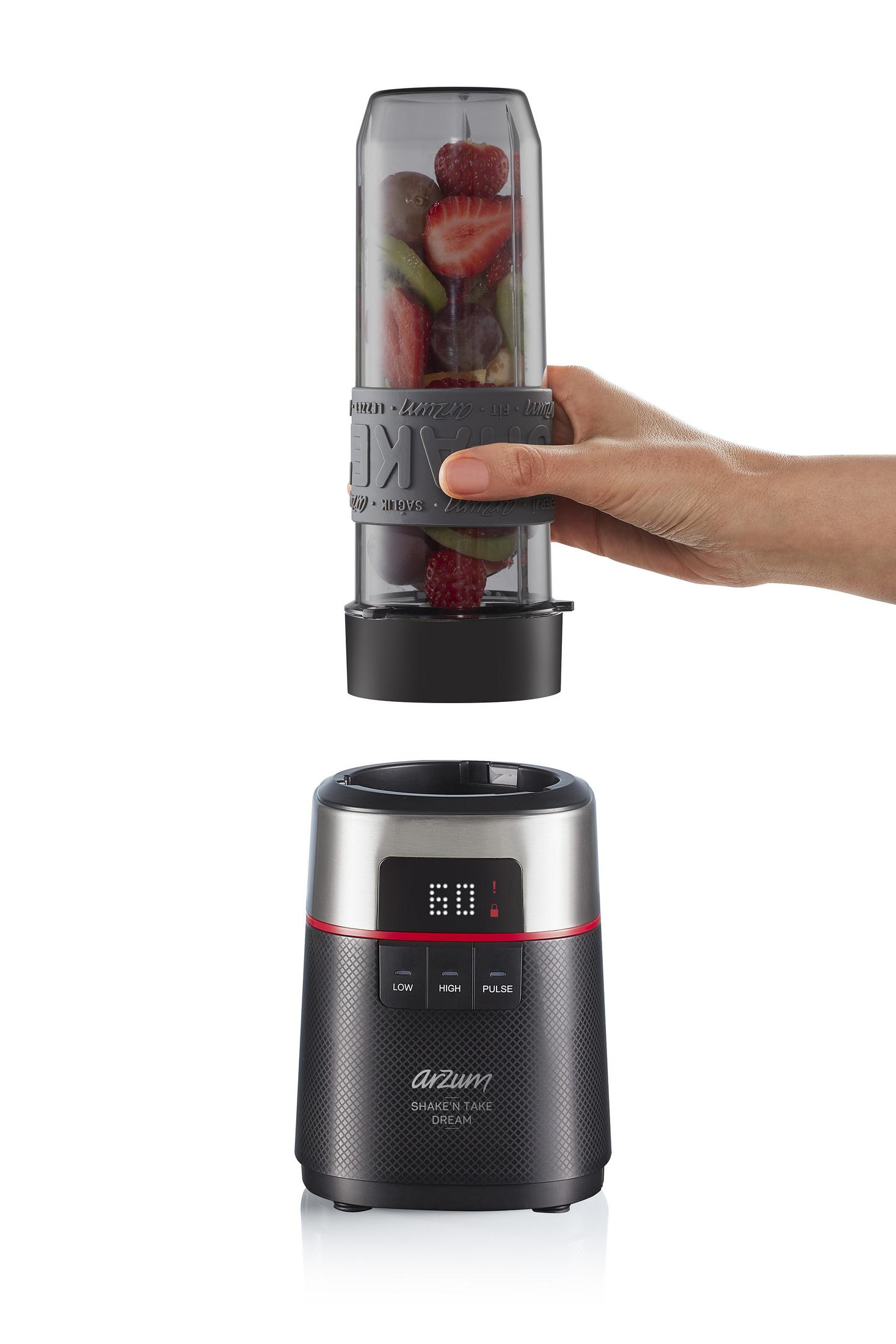 Eine Hand hält einen Mixerbehälter mit Früchten über die Basis des Mixers.
