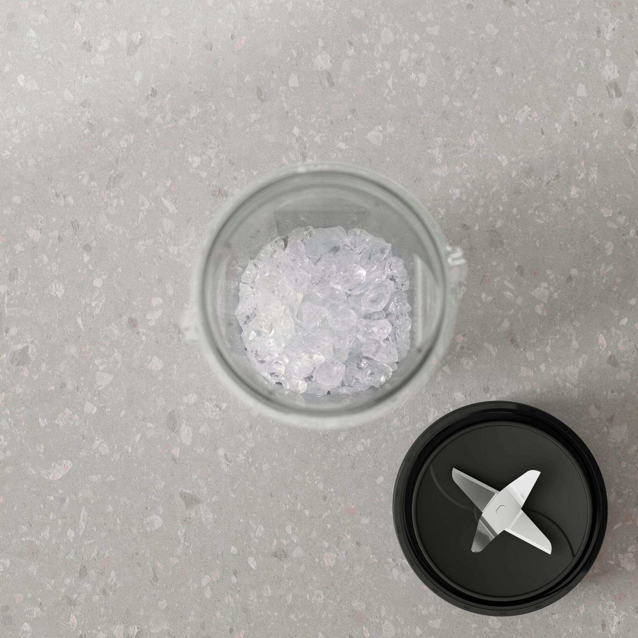 Un bicchiere pieno di ghiaccio tritato e un coperchio nero con lame.