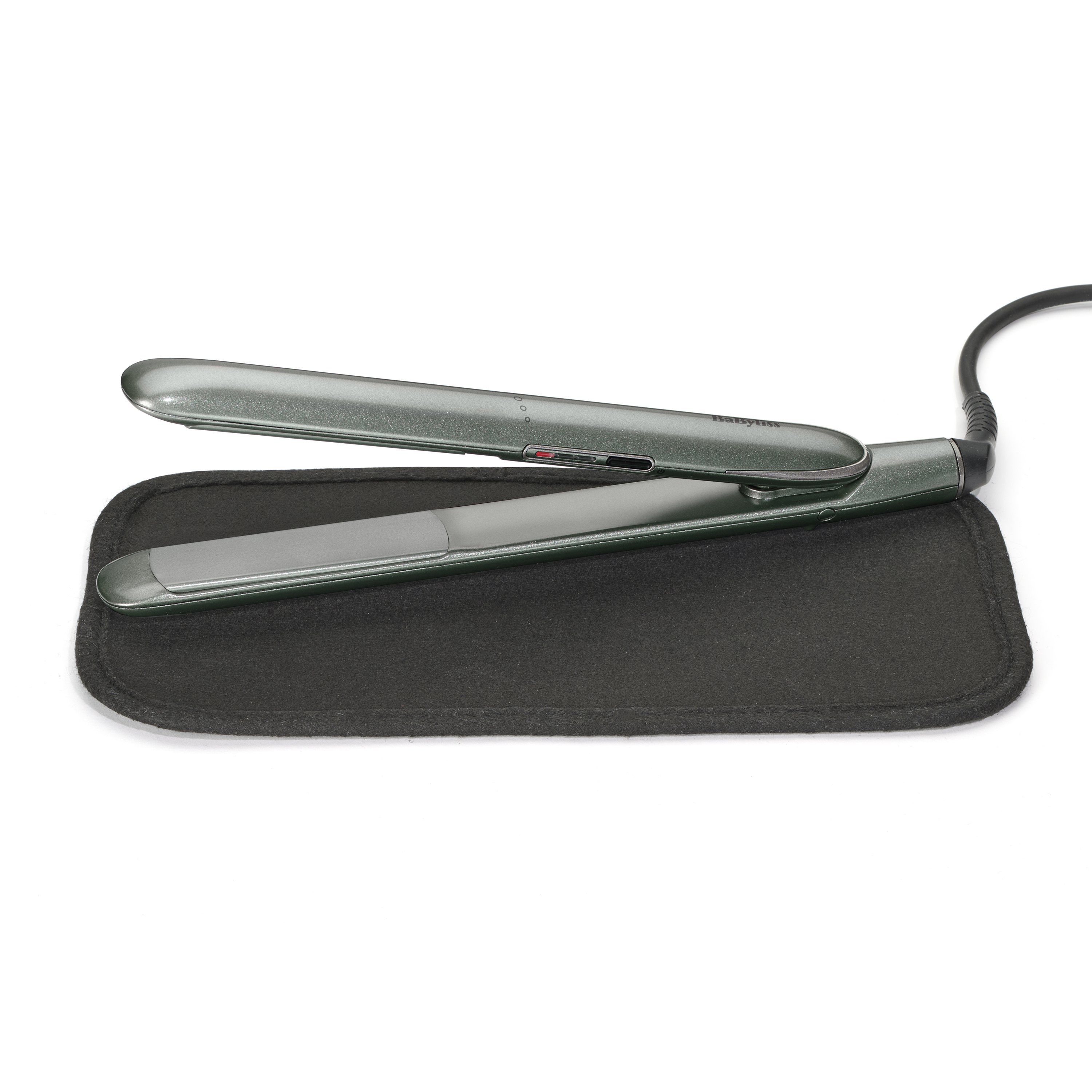 A dark green hair straightener rests on a black heat mat.