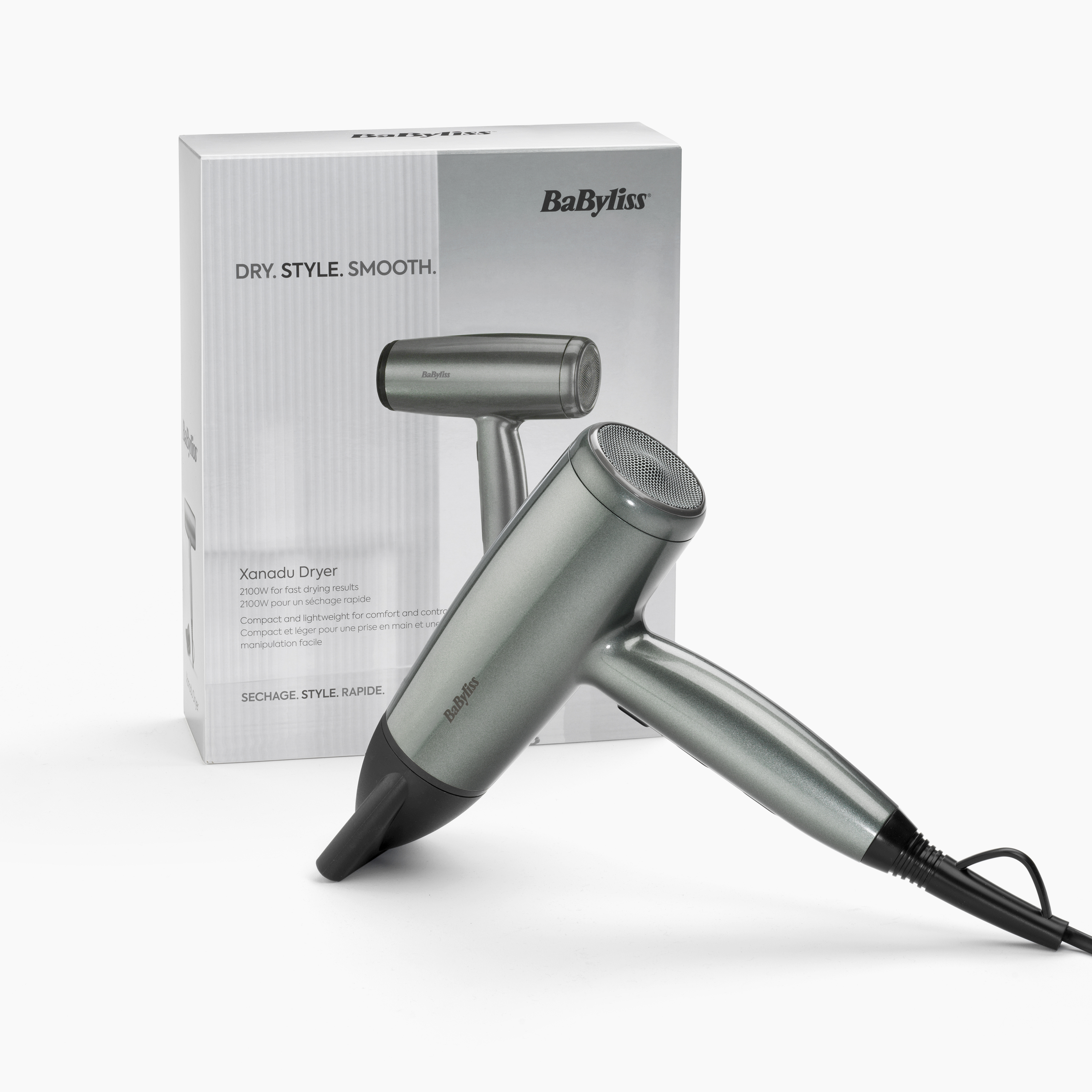 Een grijze haardroger ligt voor een bijpassende doos met het BaByliss-logo.