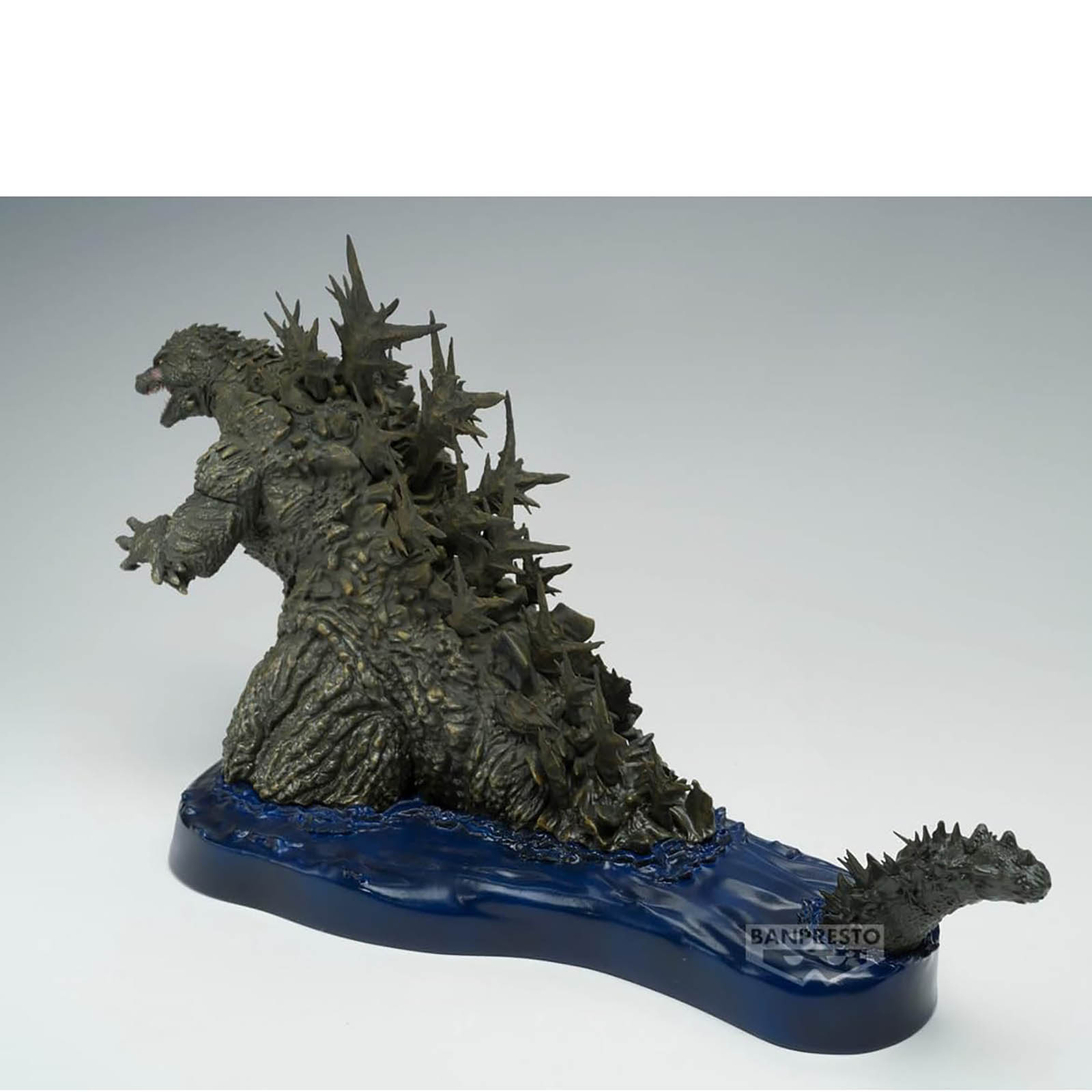 Statua di Godzilla con dorso spinoso su base blu che rappresenta l'acqua.