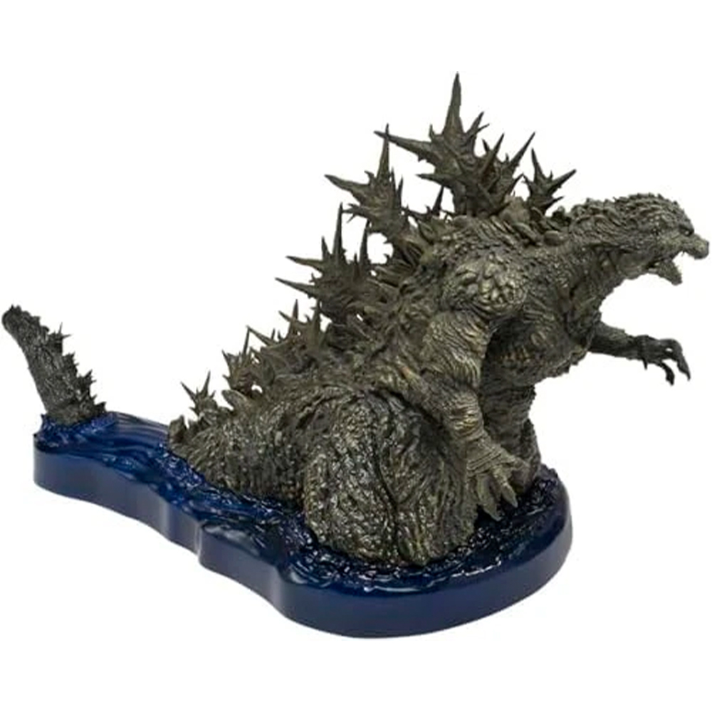 Statua di Godzilla su base blu con motivo a onde, sfondo bianco.