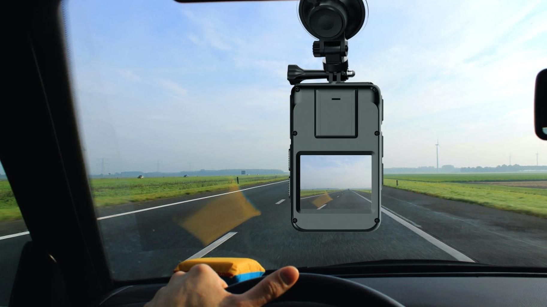 Telecamera montata sul finestrino dell'auto mostra una strada dritta con campi.