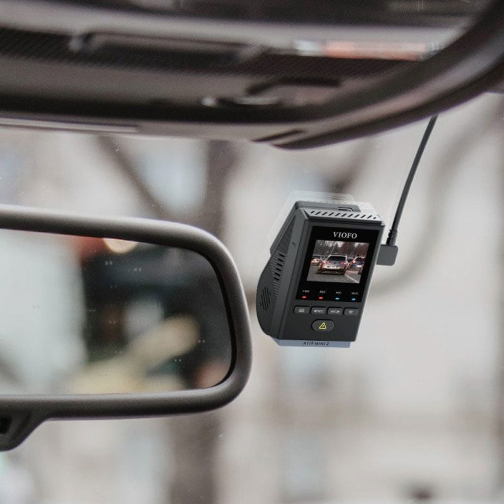 Dashcam VIOFO mostra traffico su schermo, vicino allo specchietto retrovisore.