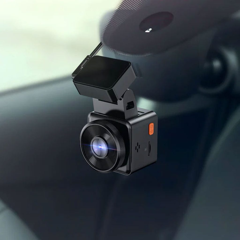 Black dashcam with lens and orange button, attached to a windshield.