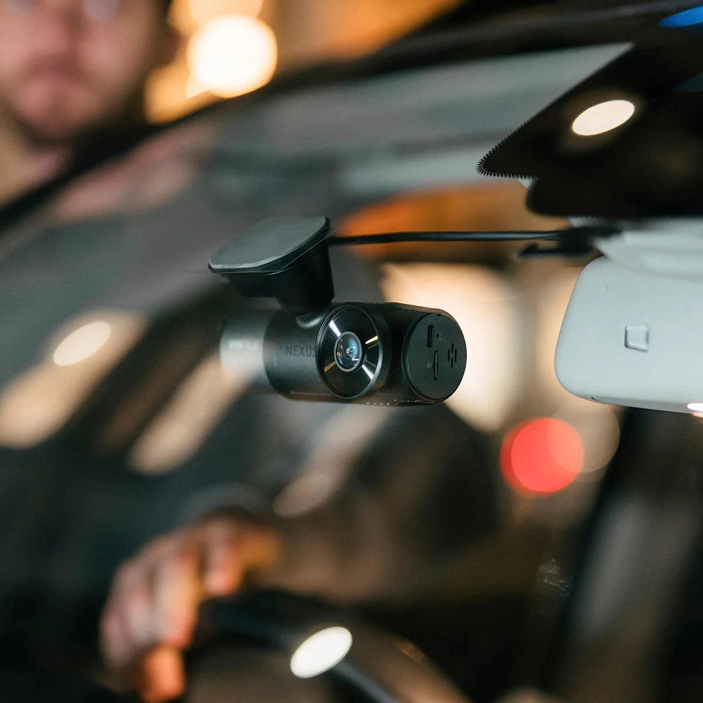 Dashboard camera with lens and ports, mounted inside a car.