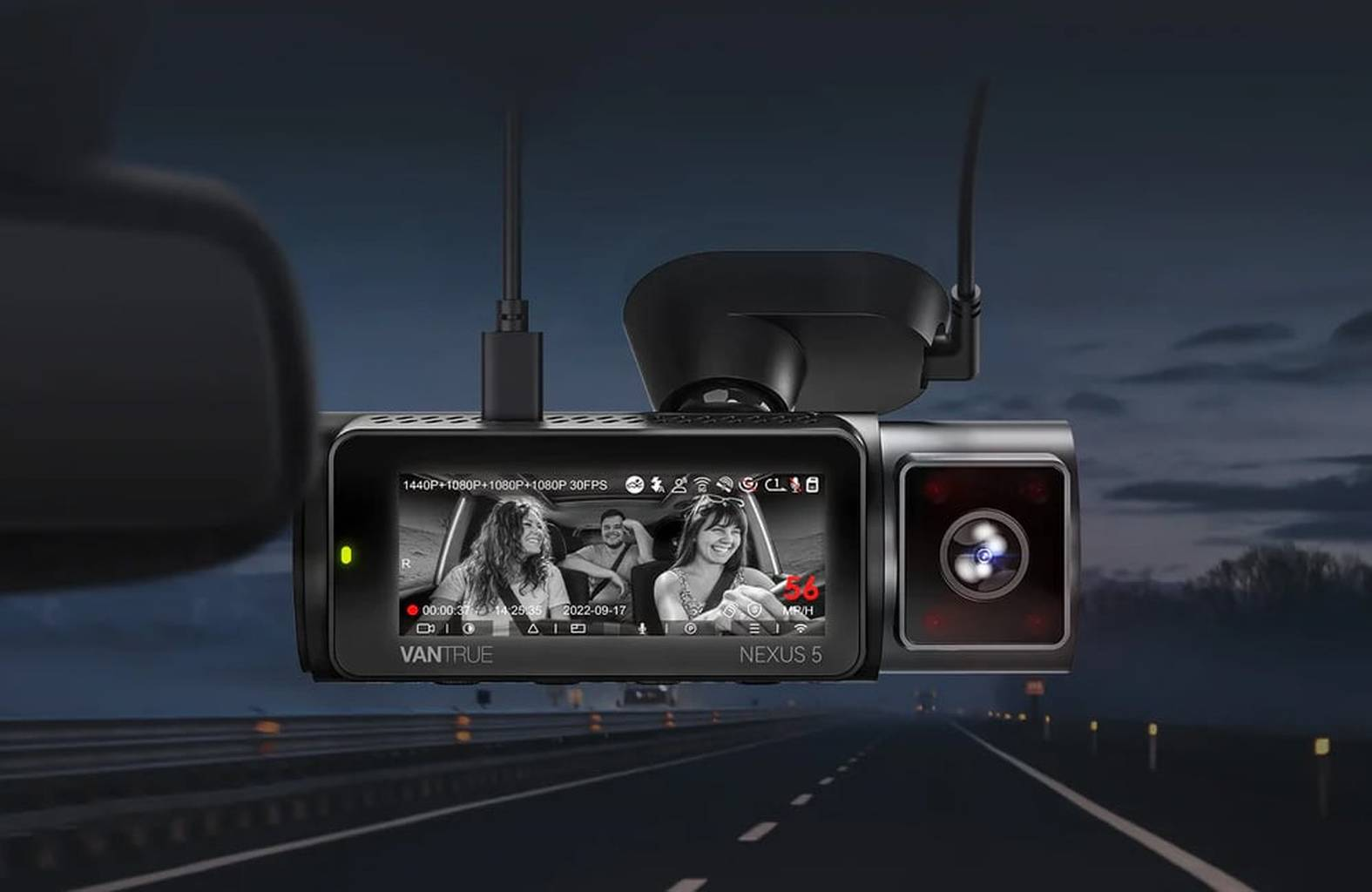 A dashcam displays two smiling people on its screen while driving.