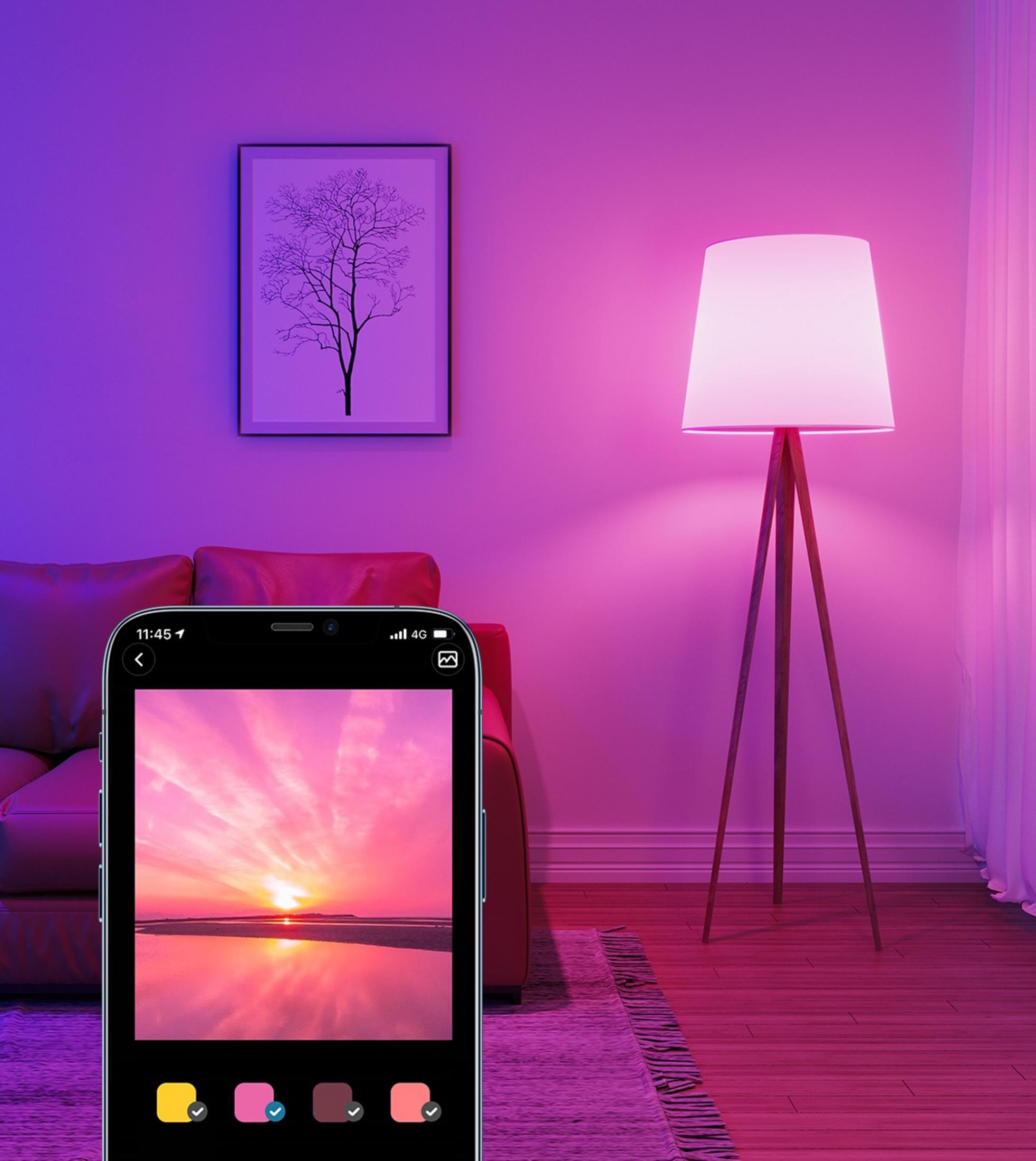 Ein Smartphone zeigt einen Sonnenuntergang, daneben ein Sofa und eine Stehlampe.