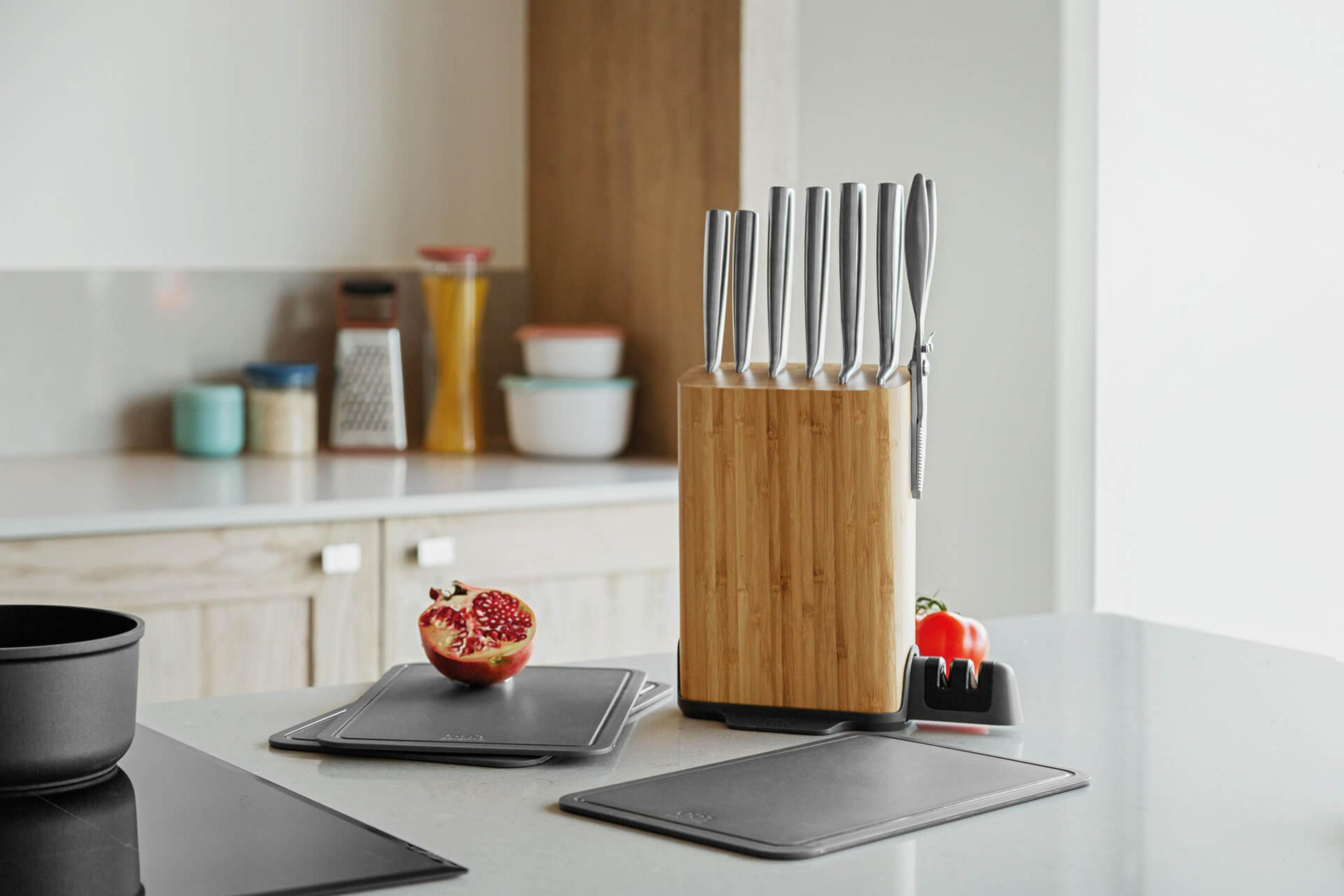 Kitchen counter with knife block, pomegranate half, and tomato.