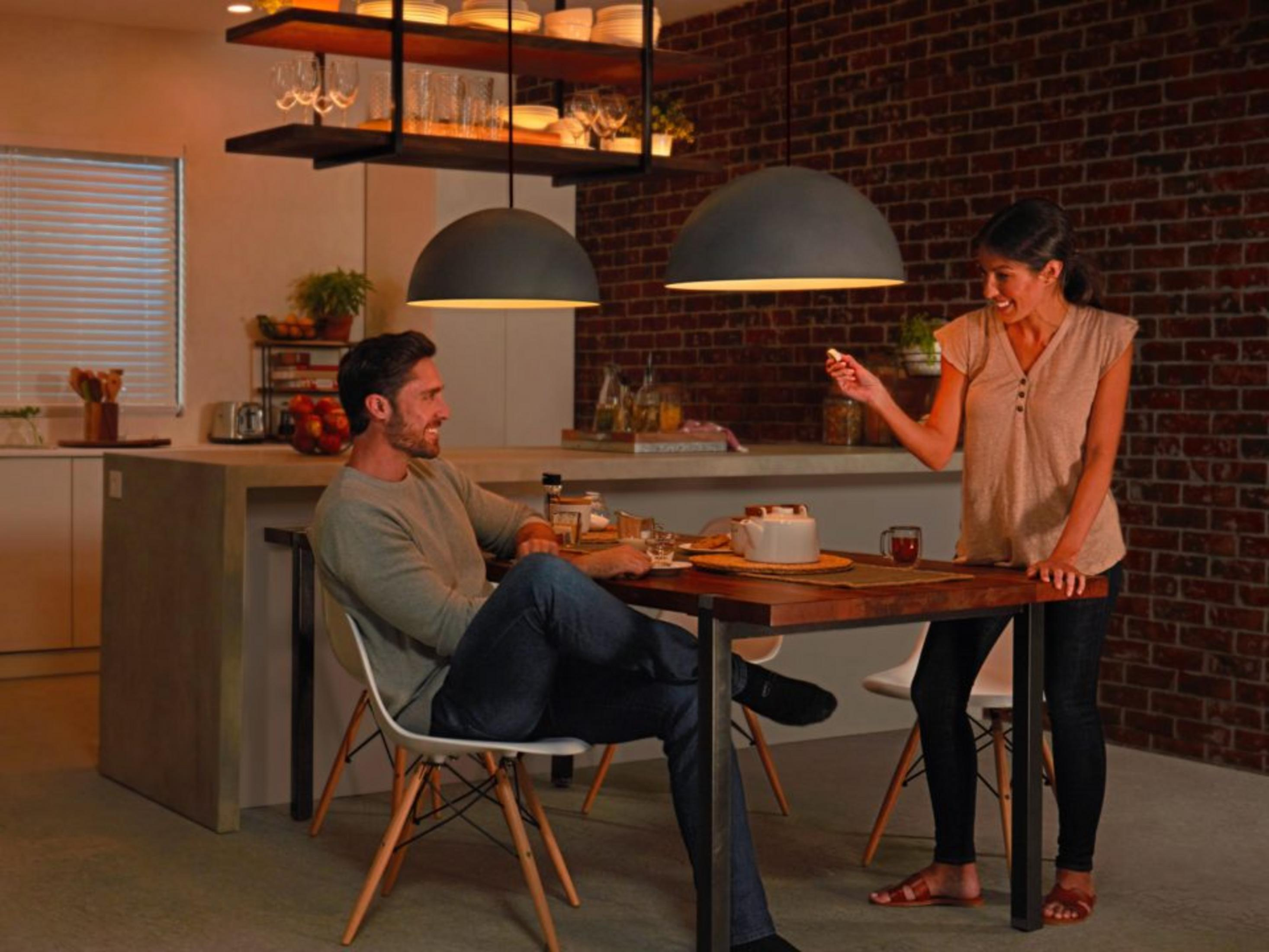 Mężczyzna i kobieta siedzą przy drewnianym stole w kuchni. Rozmawiają.