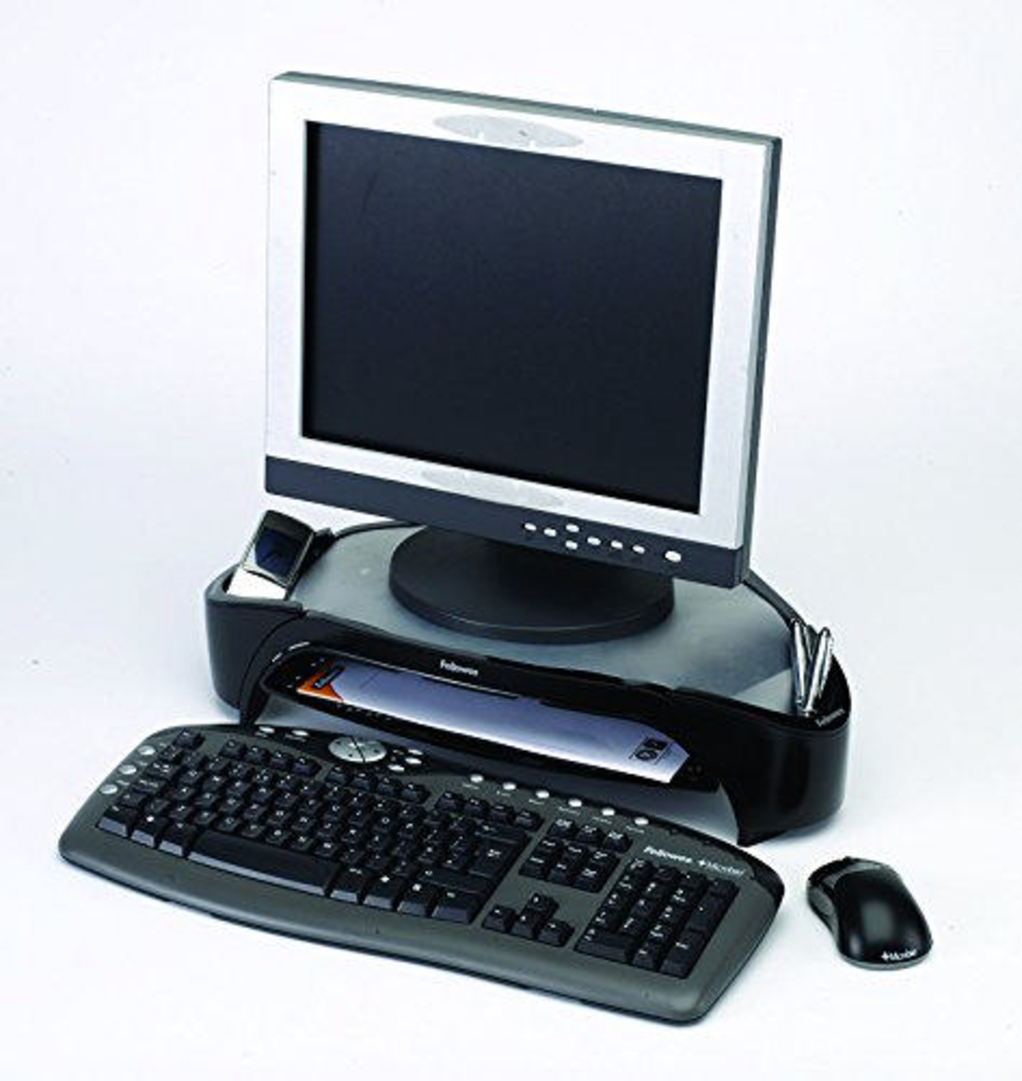 Zestaw komputerowy stacjonarny z monitorem, klawiaturą, myszą i długopisami na białym tle.