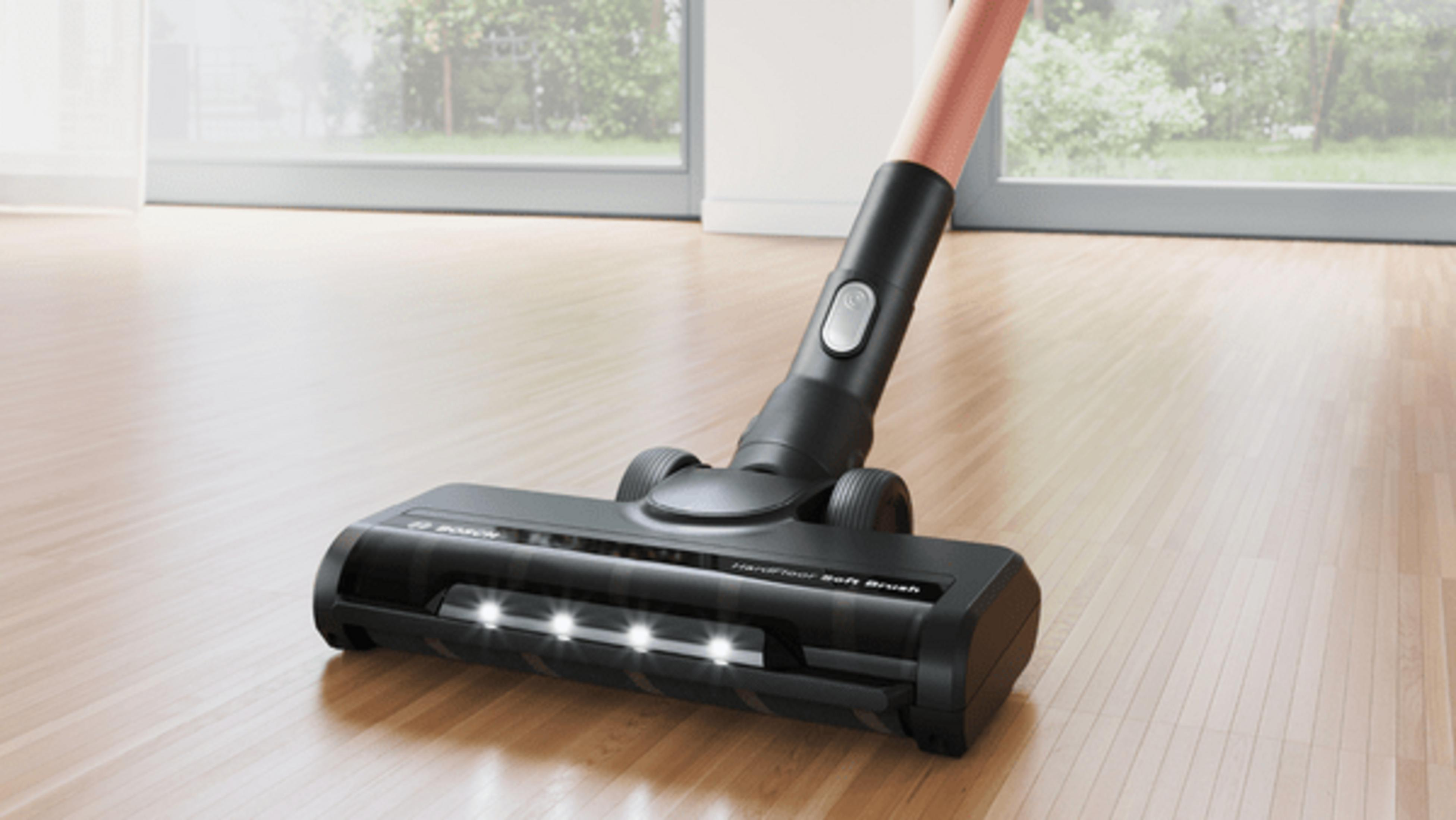 Czarna głowica odkurzacza ze światłami na drewnianej podłodze.