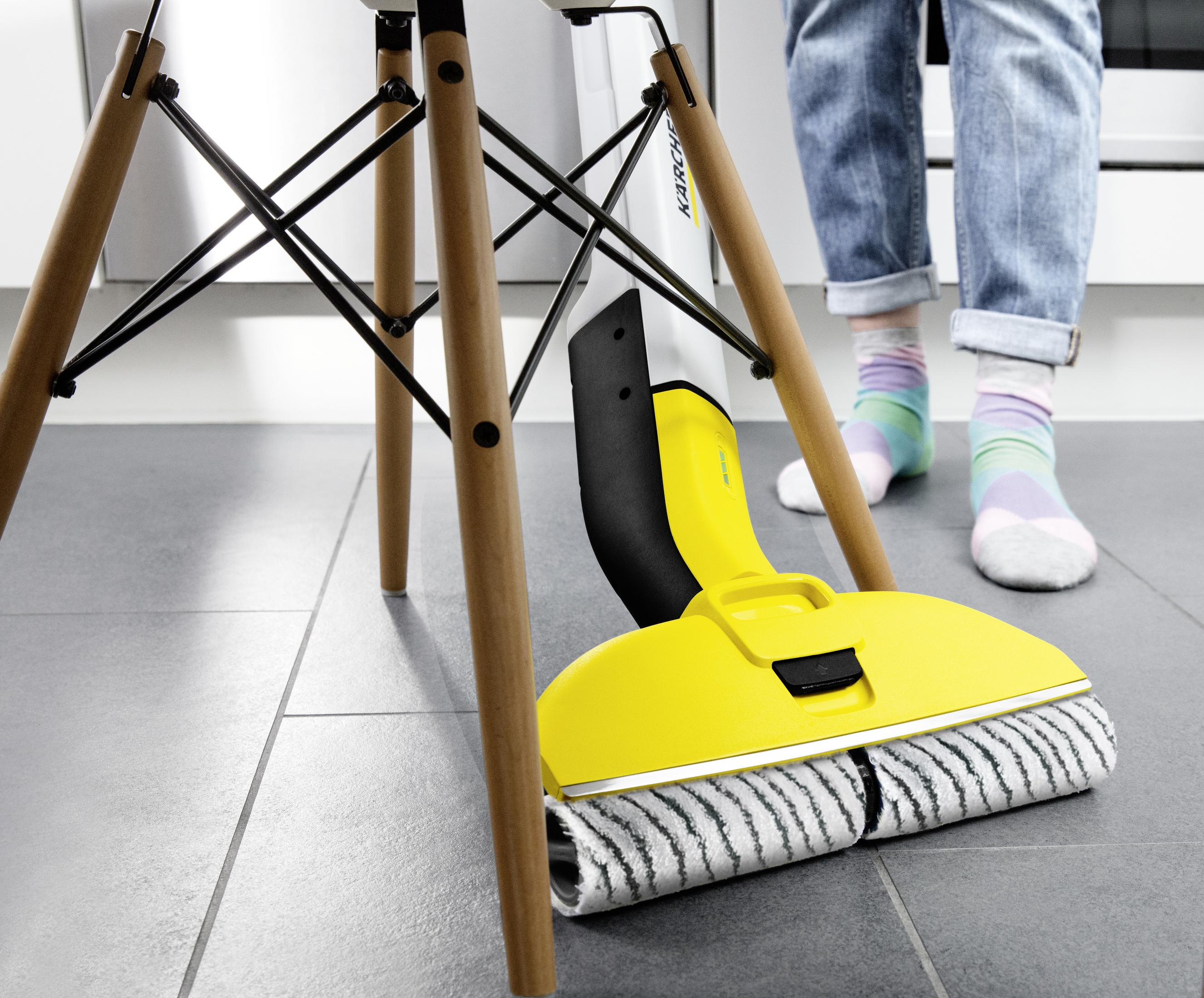 Un pulitore per pavimenti giallo è sotto una sedia. Piedi con calzini colorati si trovano nelle vicinanze.
