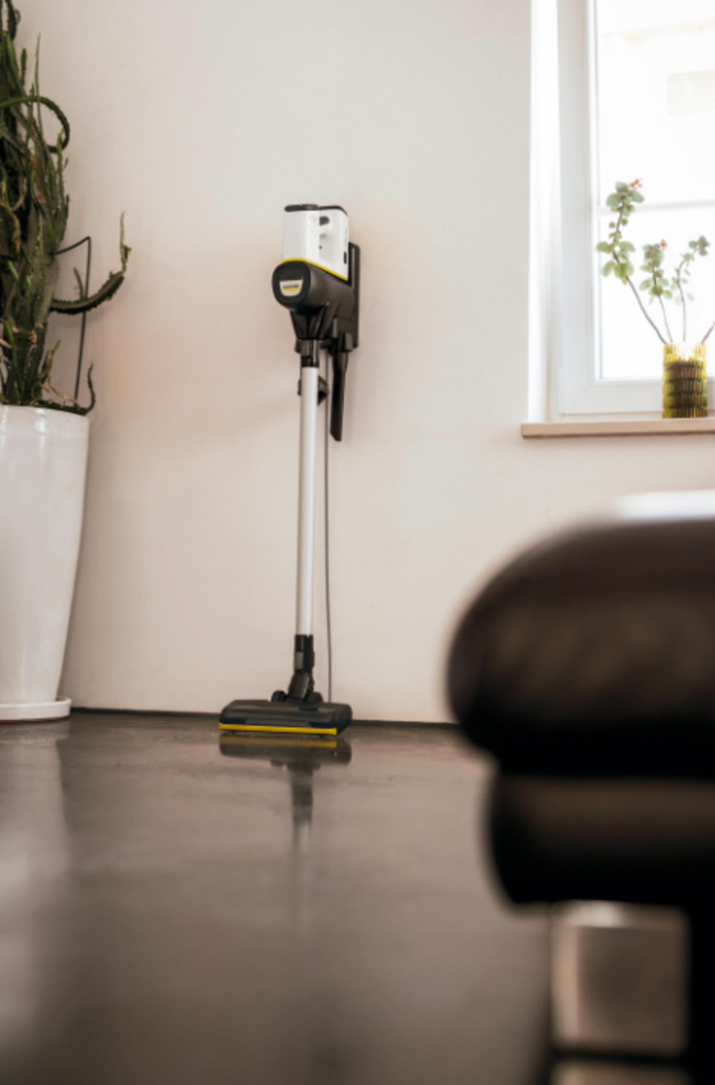 Czarny, biały i żółty odkurzacz bezprzewodowy stoi na polerowanej podłodze.
