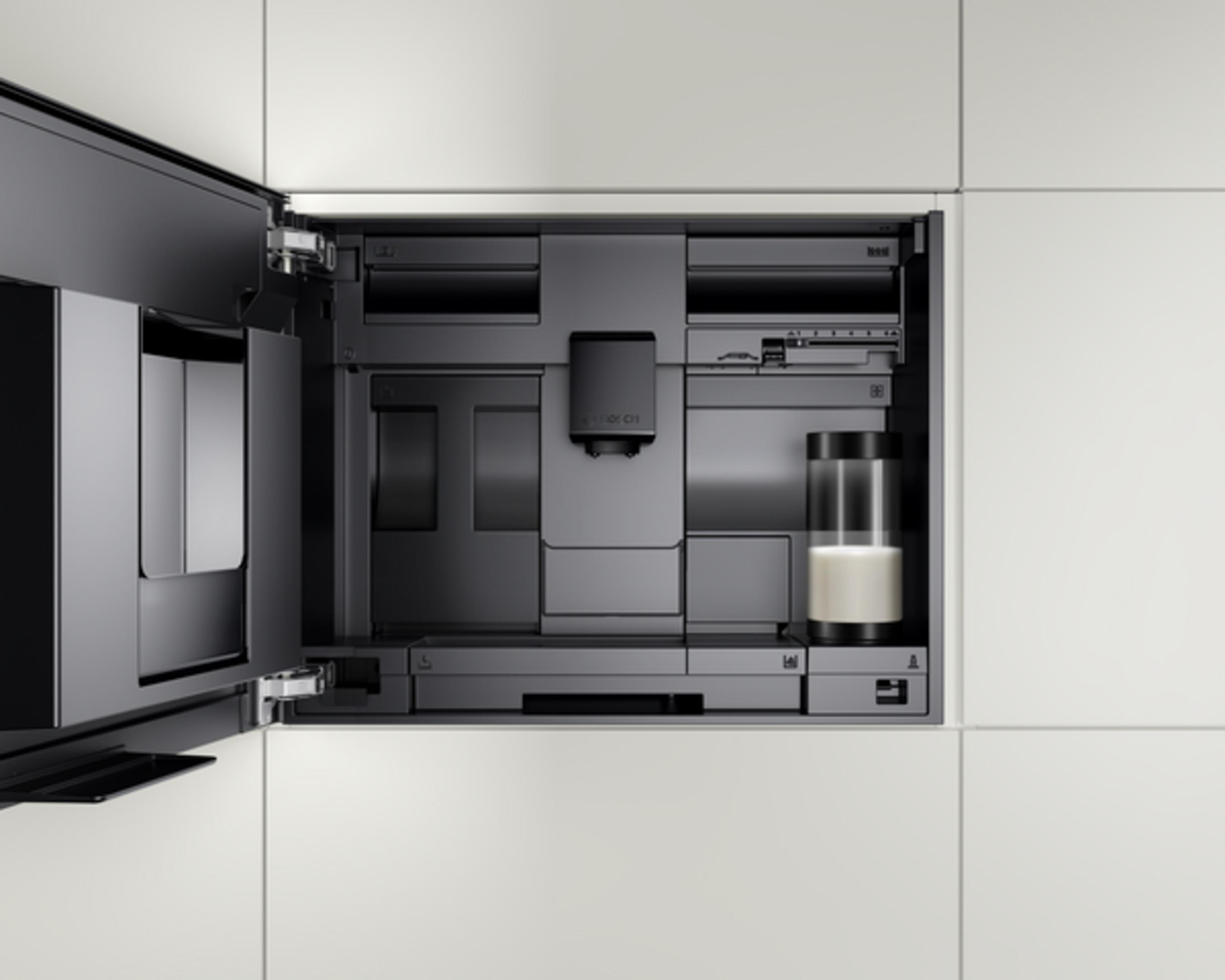 Wbudowany ekspres do kawy z pojemnikiem na mleko i otwartą klapą.