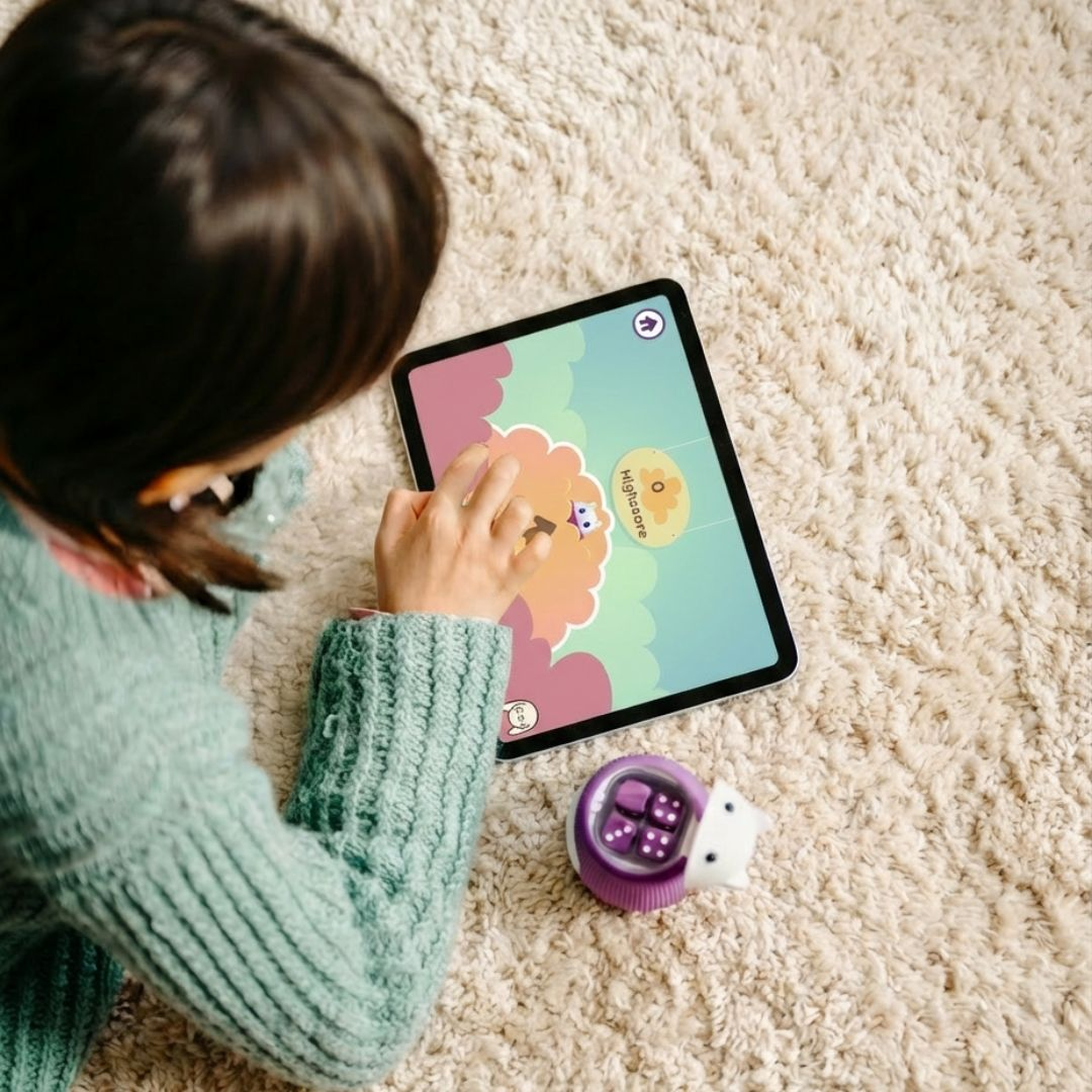 Kind spielt mit Tablet und Würfelspielzeug auf Teppich.