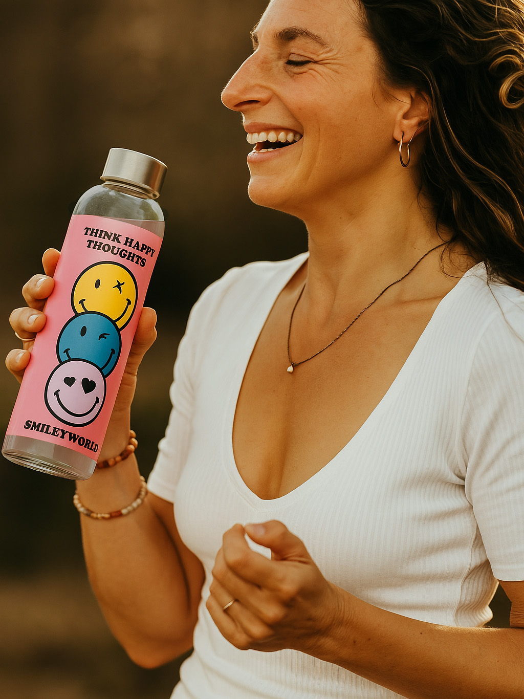 Eine Frau lacht und hält eine pinke Flasche mit Smiley-Gesichtern.