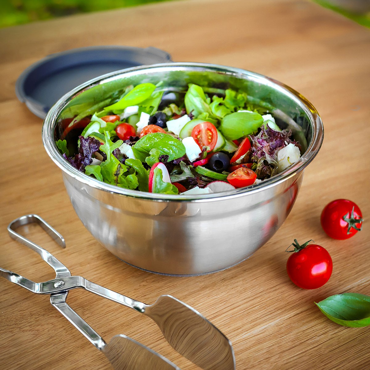 Ein Edelstahlsalat mit Tomaten, Gurken, Oliven, Feta und Basilikum.
