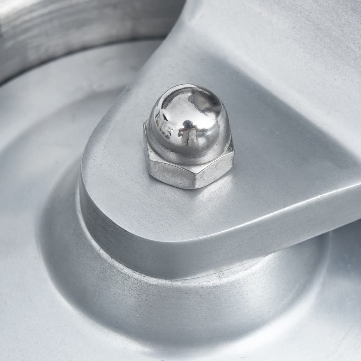 Nahaufnahme einer silbernen Mutter mit einer runden Kappe auf einer Metallplatte.
