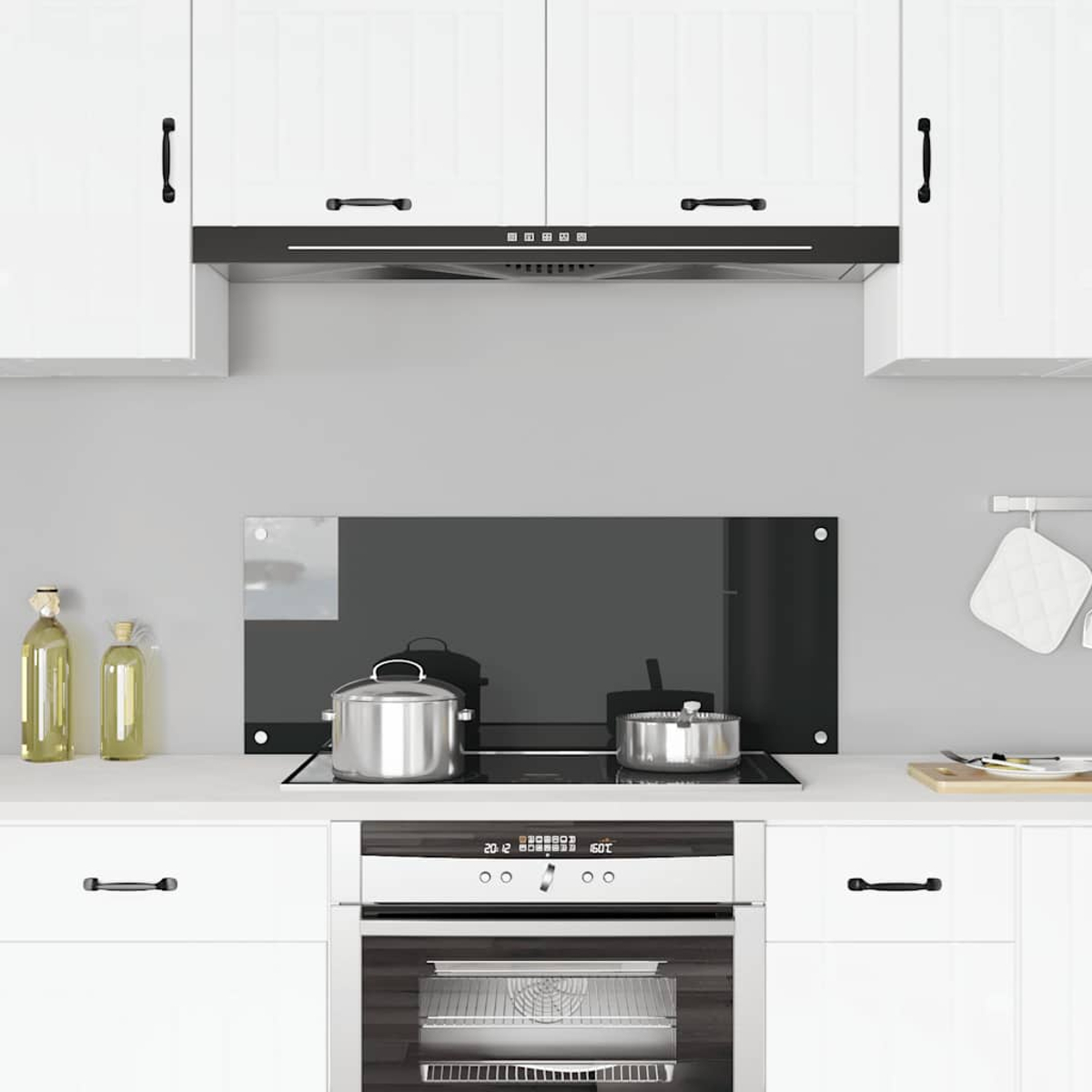 Cocina moderna con gabinetes blancos, estufa negra y ollas plateadas.