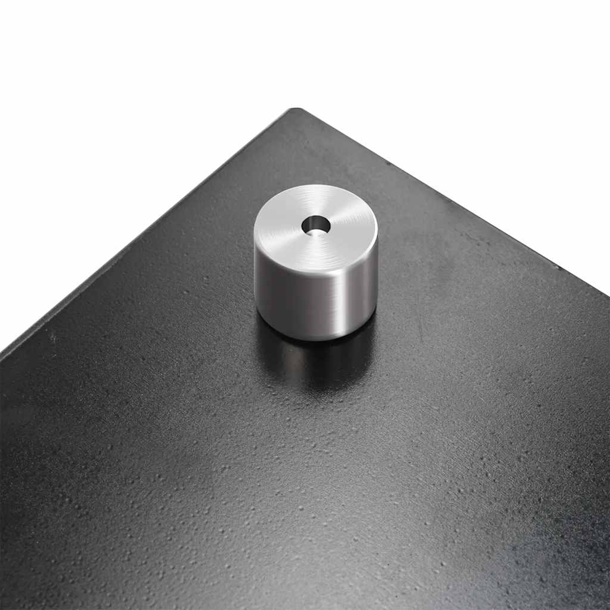 Ein zylindrischer Metallstift mit Loch auf einer schwarzen Platte.