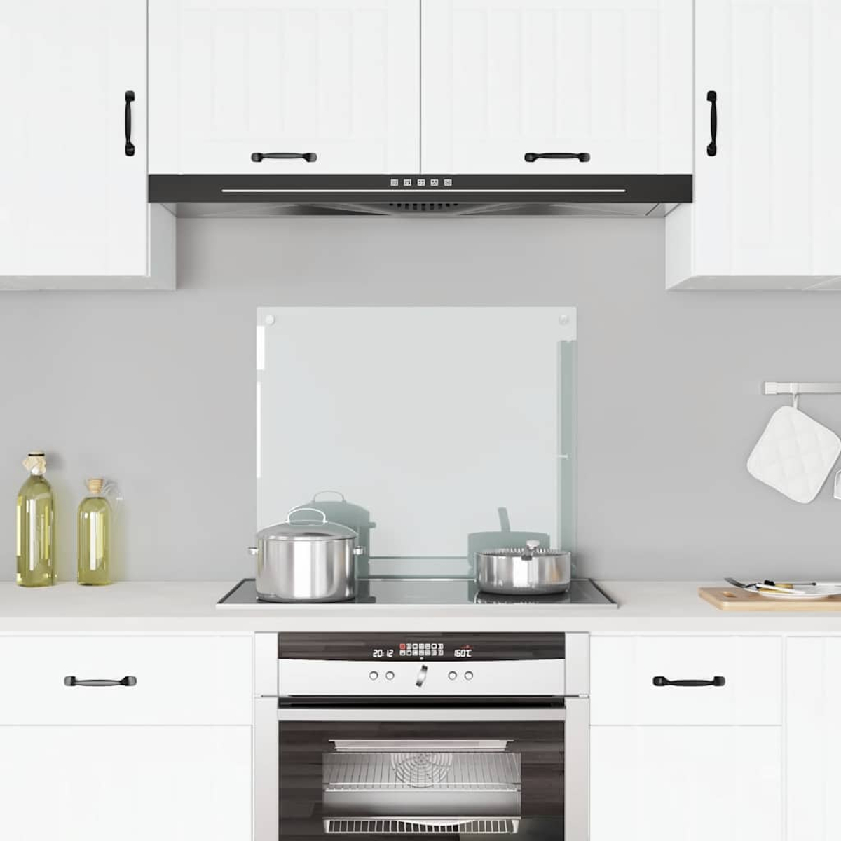 Una cocina blanca con vitrocerámica, horno y utensilios en la encimera.