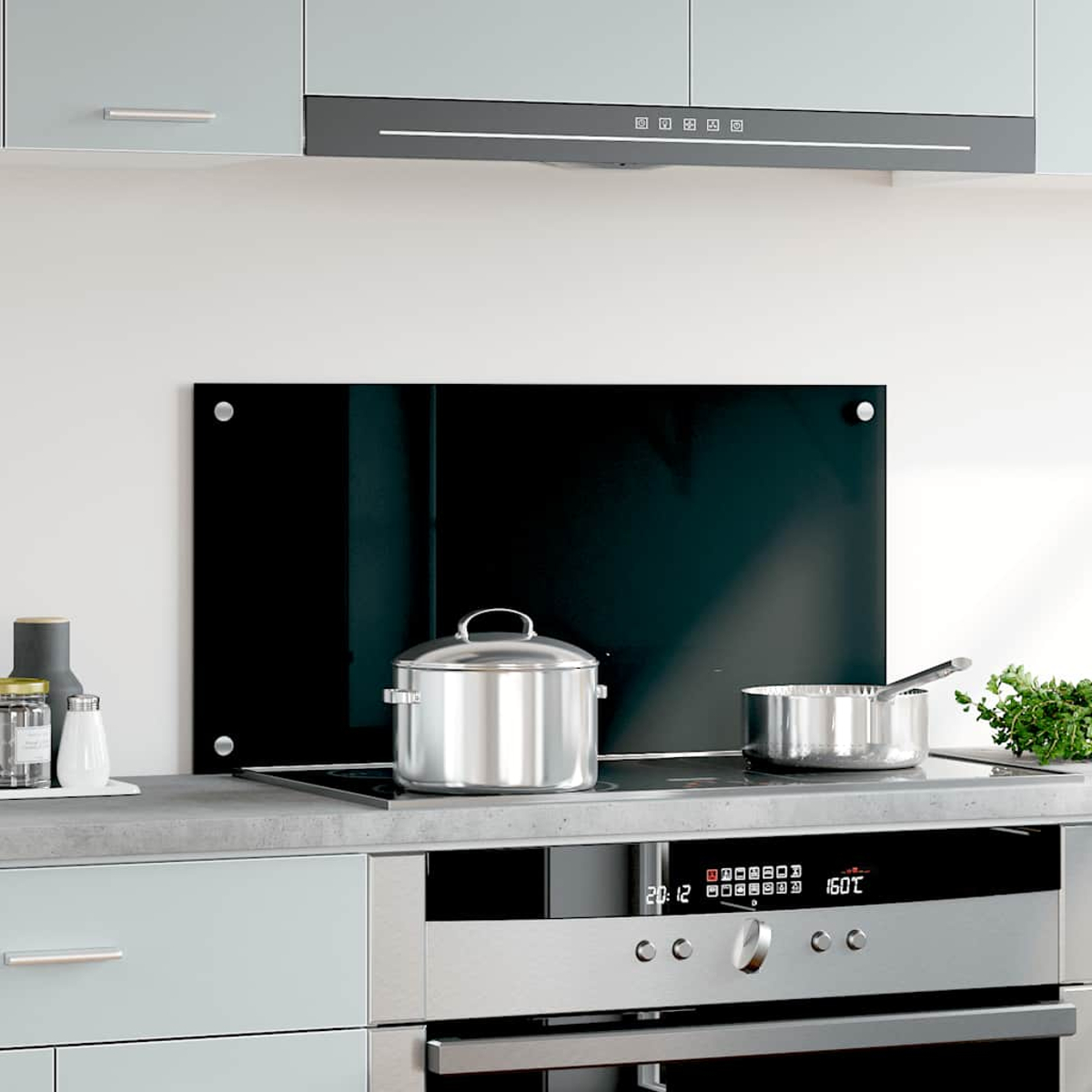 Una cocina moderna con ollas de acero inoxidable en una placa de cocina, frente a un protector contra salpicaduras negro.
