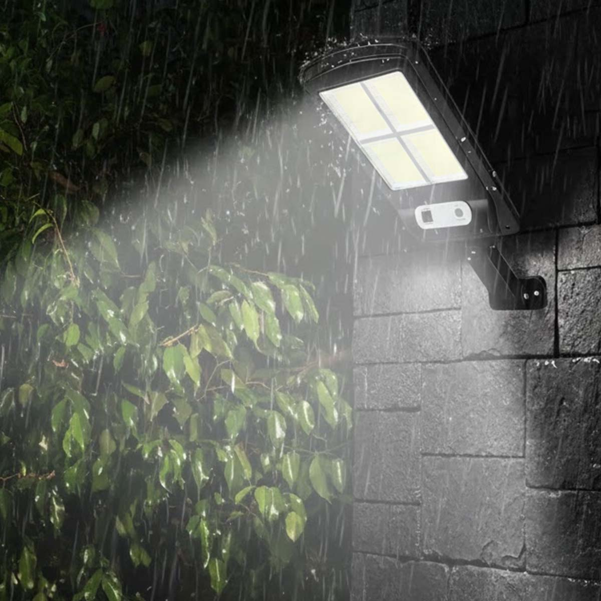 Eine Solarleuchte leuchtet auf eine Mauer, während es regnet.