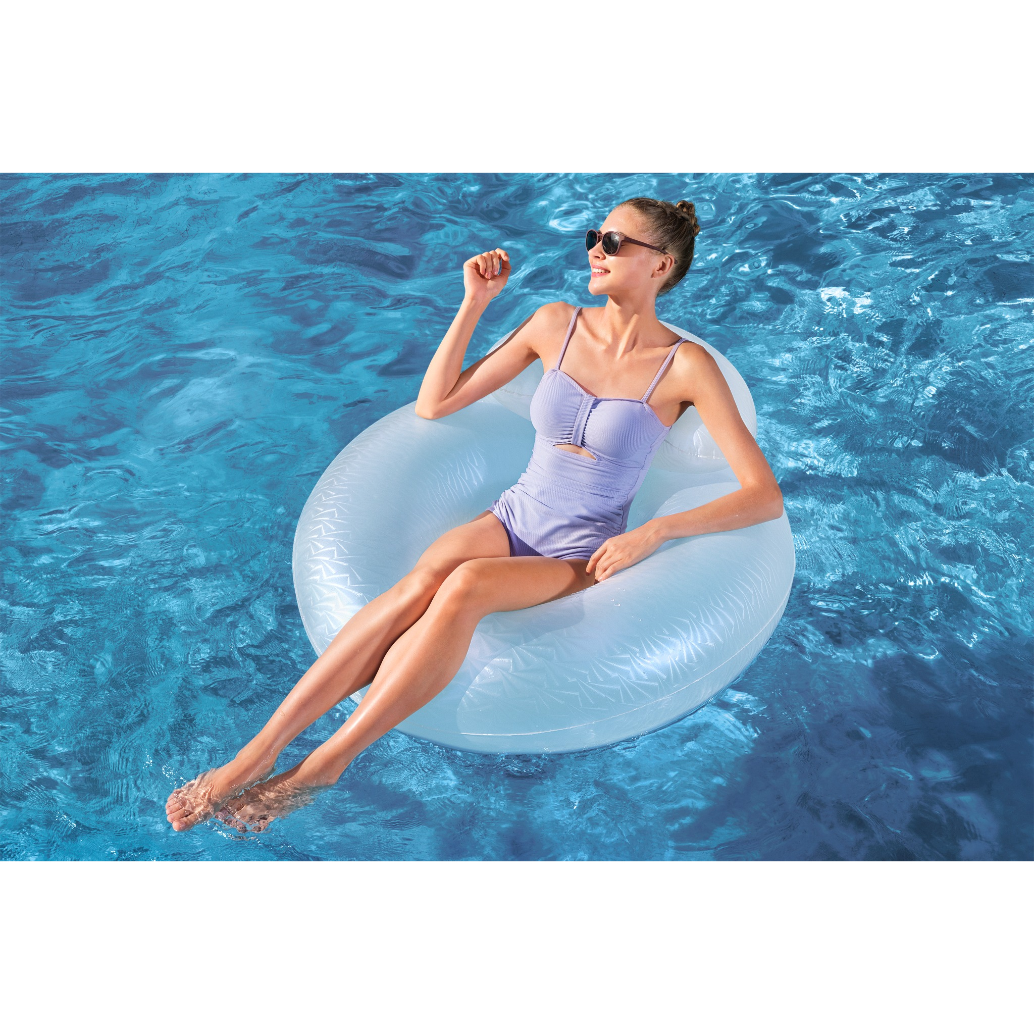 Frau in lila Badeanzug entspannt auf weißem Schwimmring im blauen Wasser.