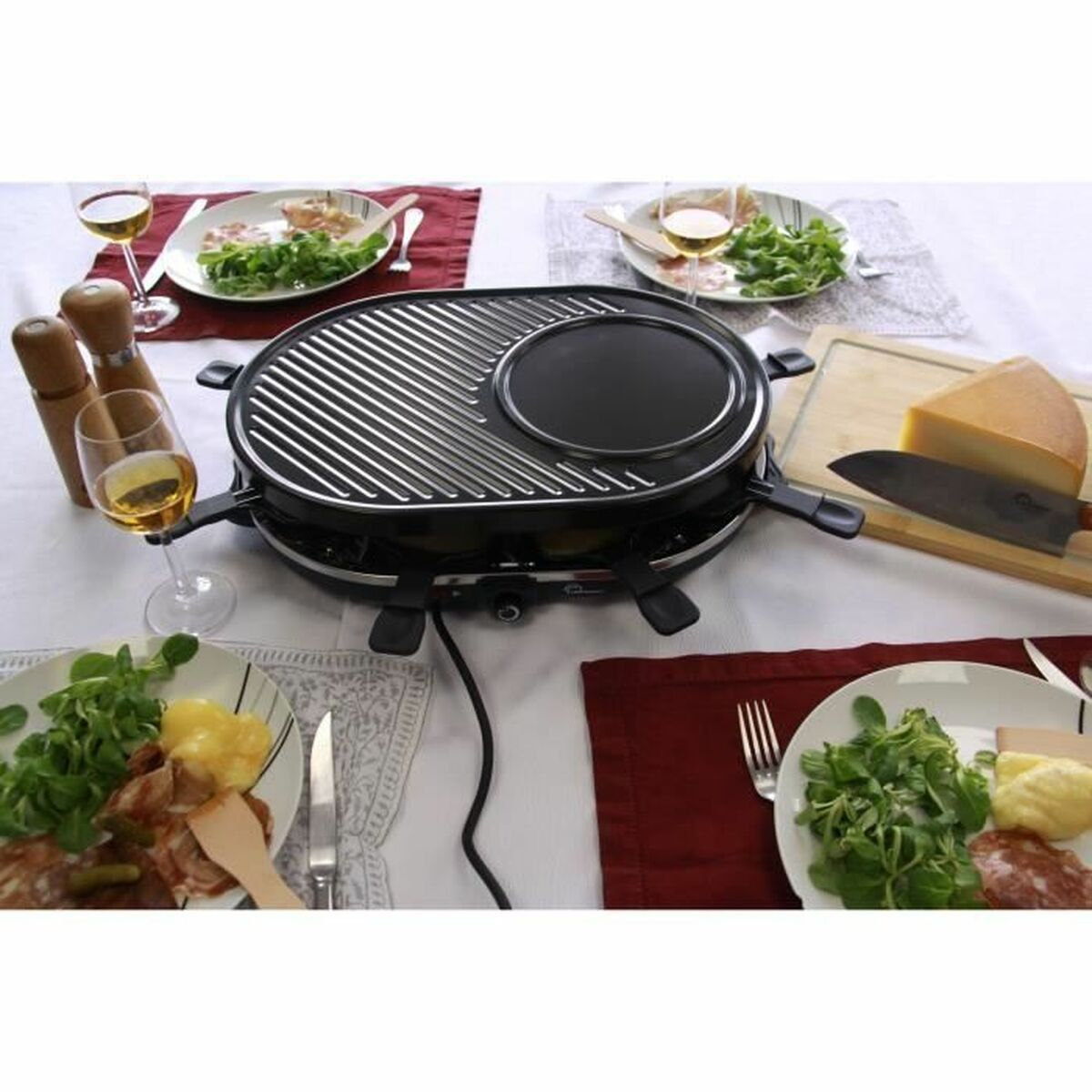 Ein Raclette-Grill mit Grillfläche, Käse, Messer und Essen auf einem Tisch.