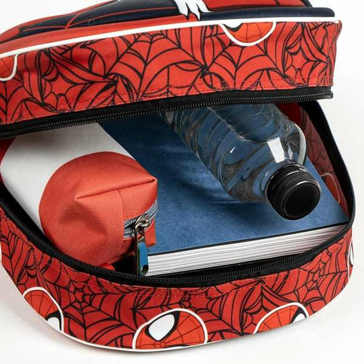 Ein roter Rucksack mit Spiderman-Motiv, gefüllt mit einem Buch, Stifteetui und Wasserflasche.