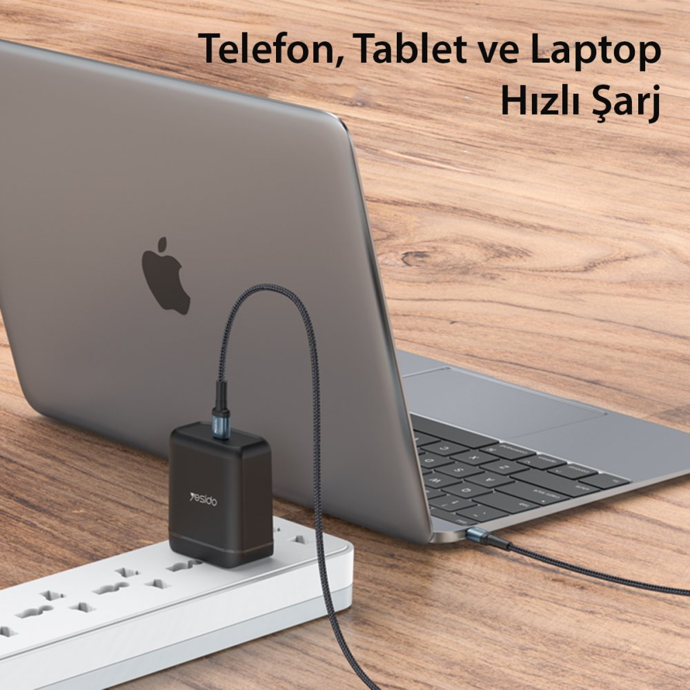 Beyaz bir prize takılı siyah şarj adaptörü, bir dizüstü bilgisayarı şarj ediyor.