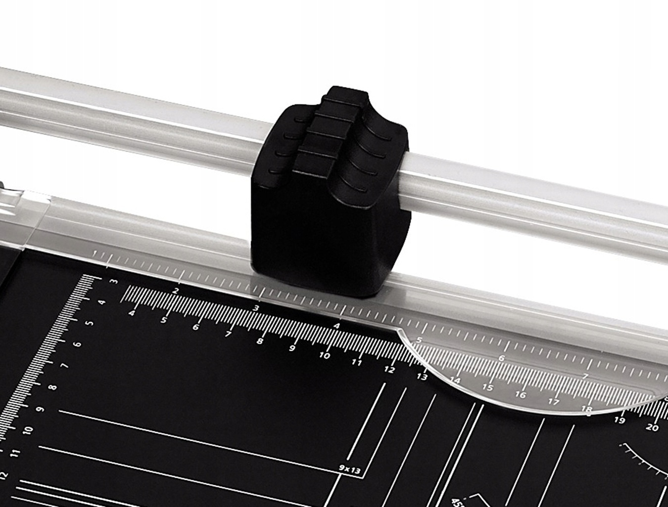 Zbliżenie czarnej gilotyny do papieru z srebrnymi prowadnicami i czarną głowicą tnącą.