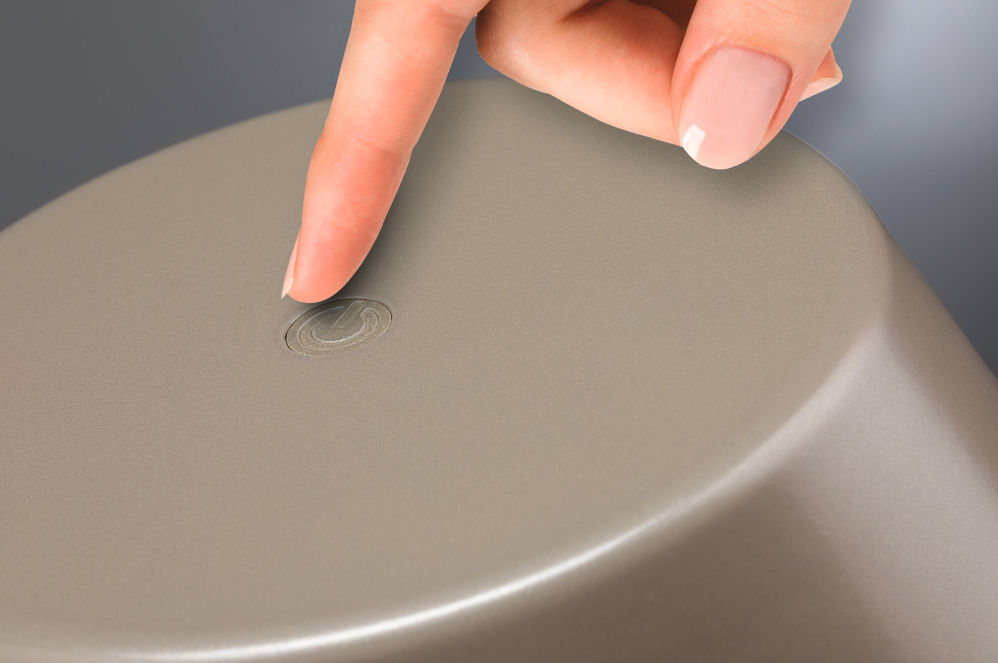 Palec naciska mały szary symbol na beżowym obiekcie.